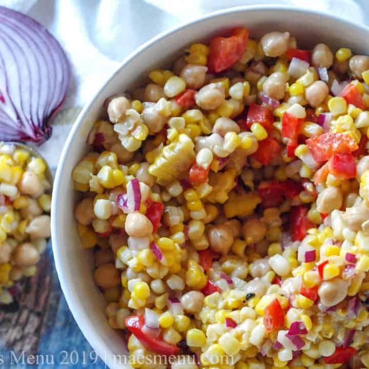 Large white bowl of Chickpea & Grilled Corn Salad with Roasted Garlic Salad Dressing.