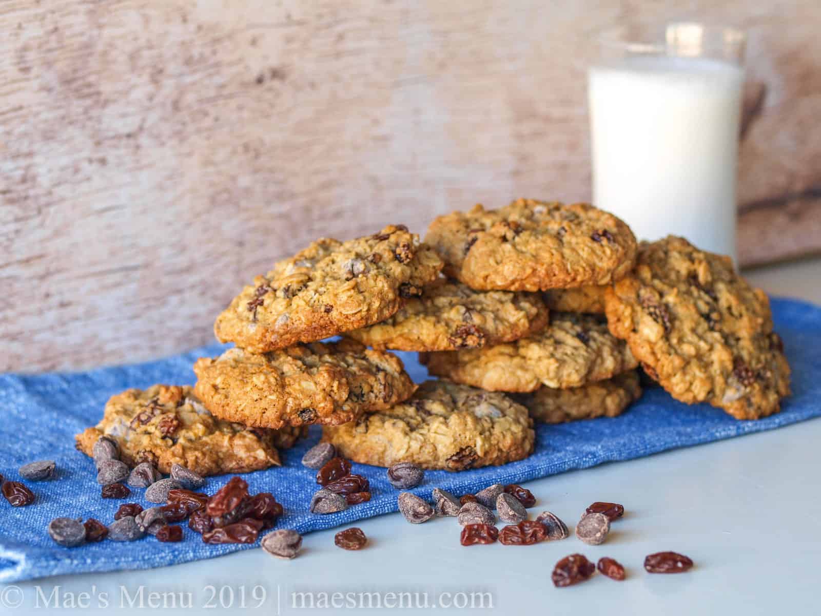 Stack of oatmeal raisin chocolate chip cookies next to a glass of milk.