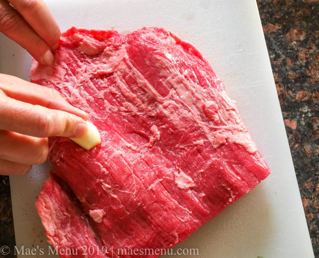 Rubbing the steak with a clove of garlic.