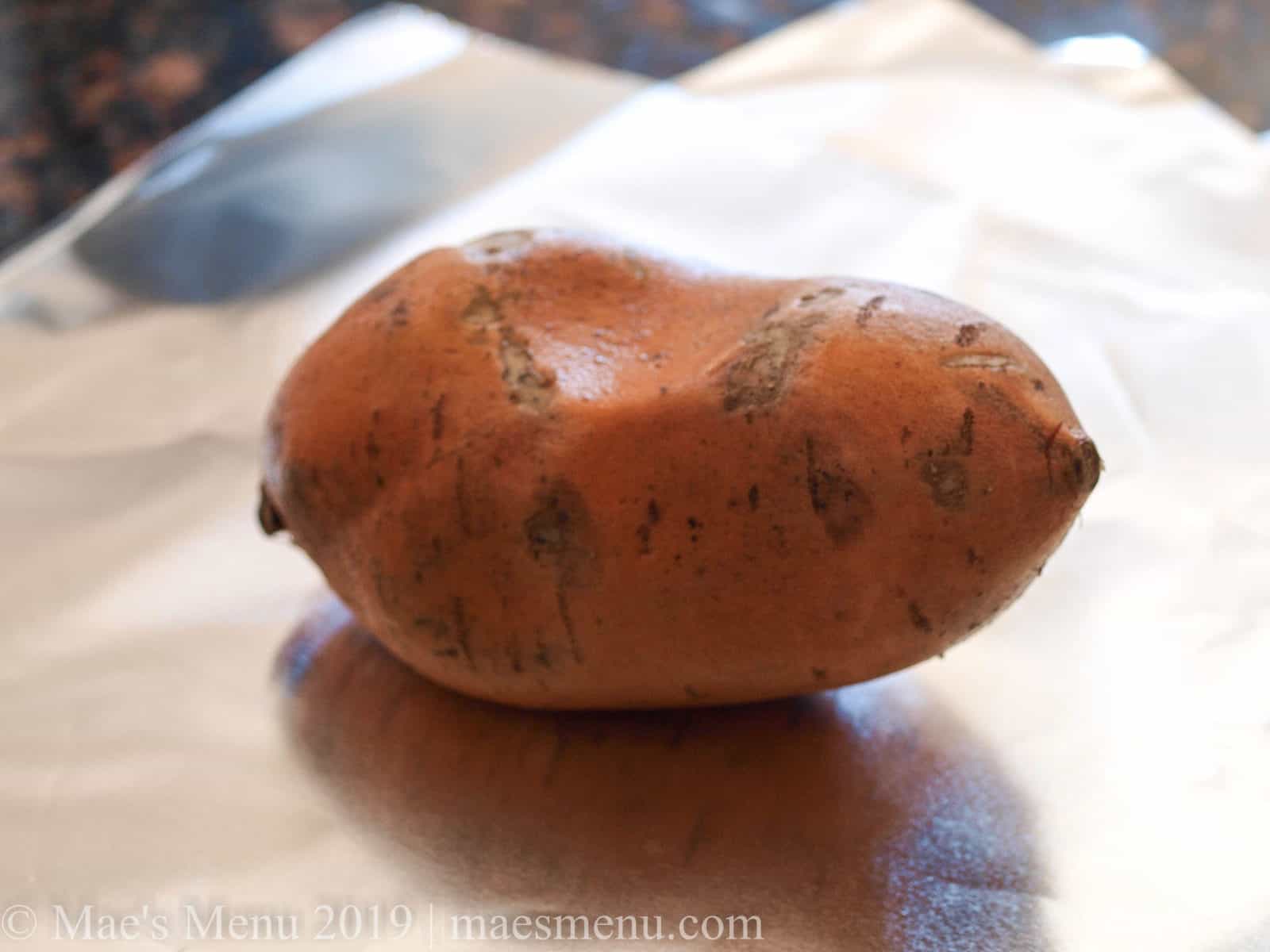 A sweet potato on a piece of aluminum foil 