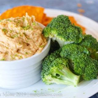 Small dish of curry hummus with chips and broccoli.