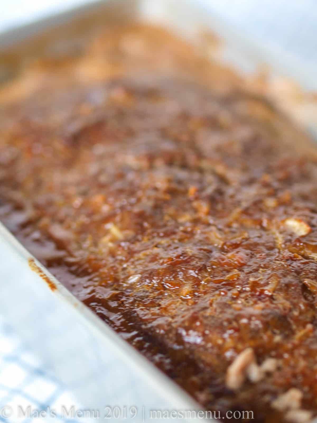 A side angle shot of a loaf pan full of teriyaki meatloaf