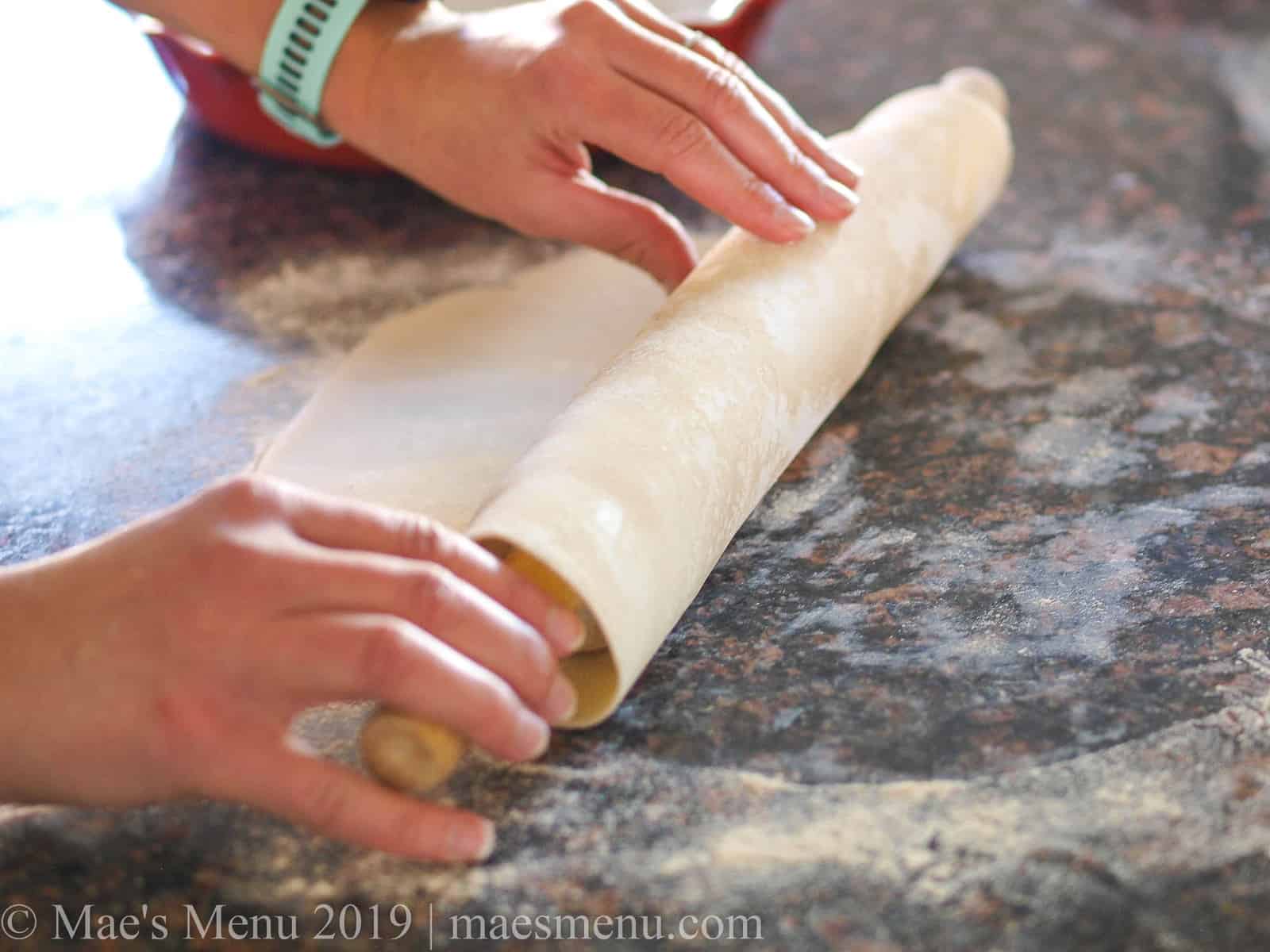 Rolling a pie crust up on a rolling pin