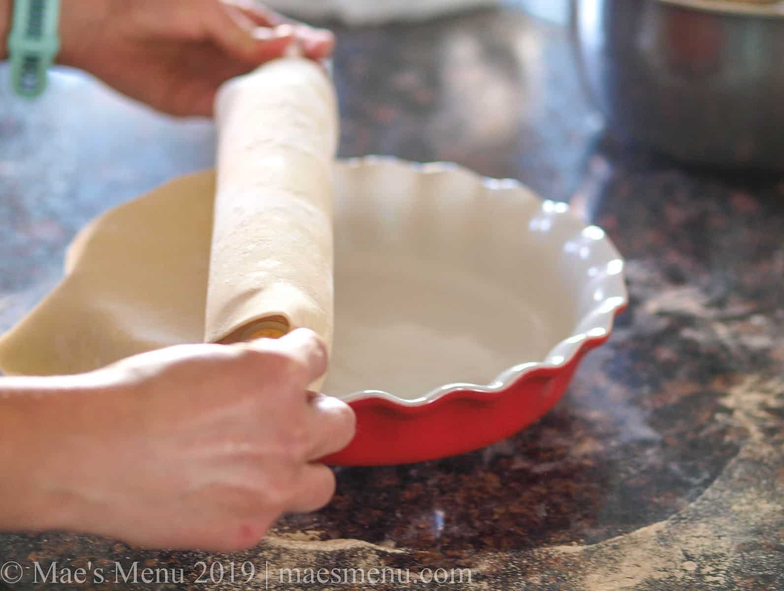Rolling a pie crust out over a pie pan. 