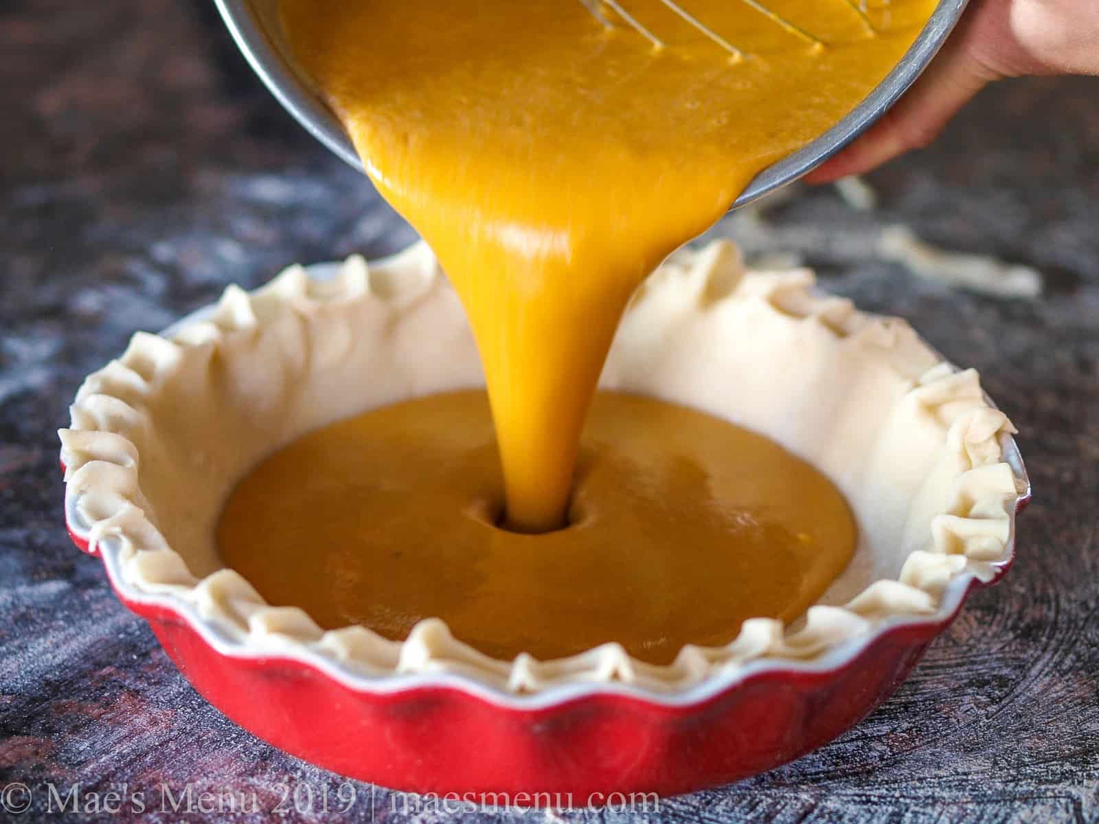 Pouring the pumpkin pie filling into an unbaked pie shell