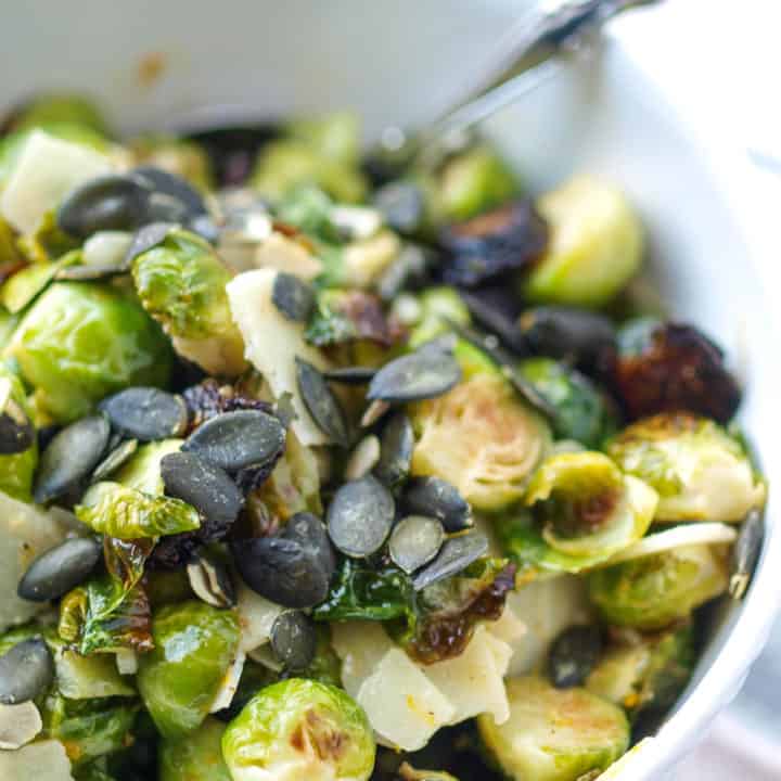 A large bowl of healthy roasted brussels sprouts with manchego, dried figs, and pepitas