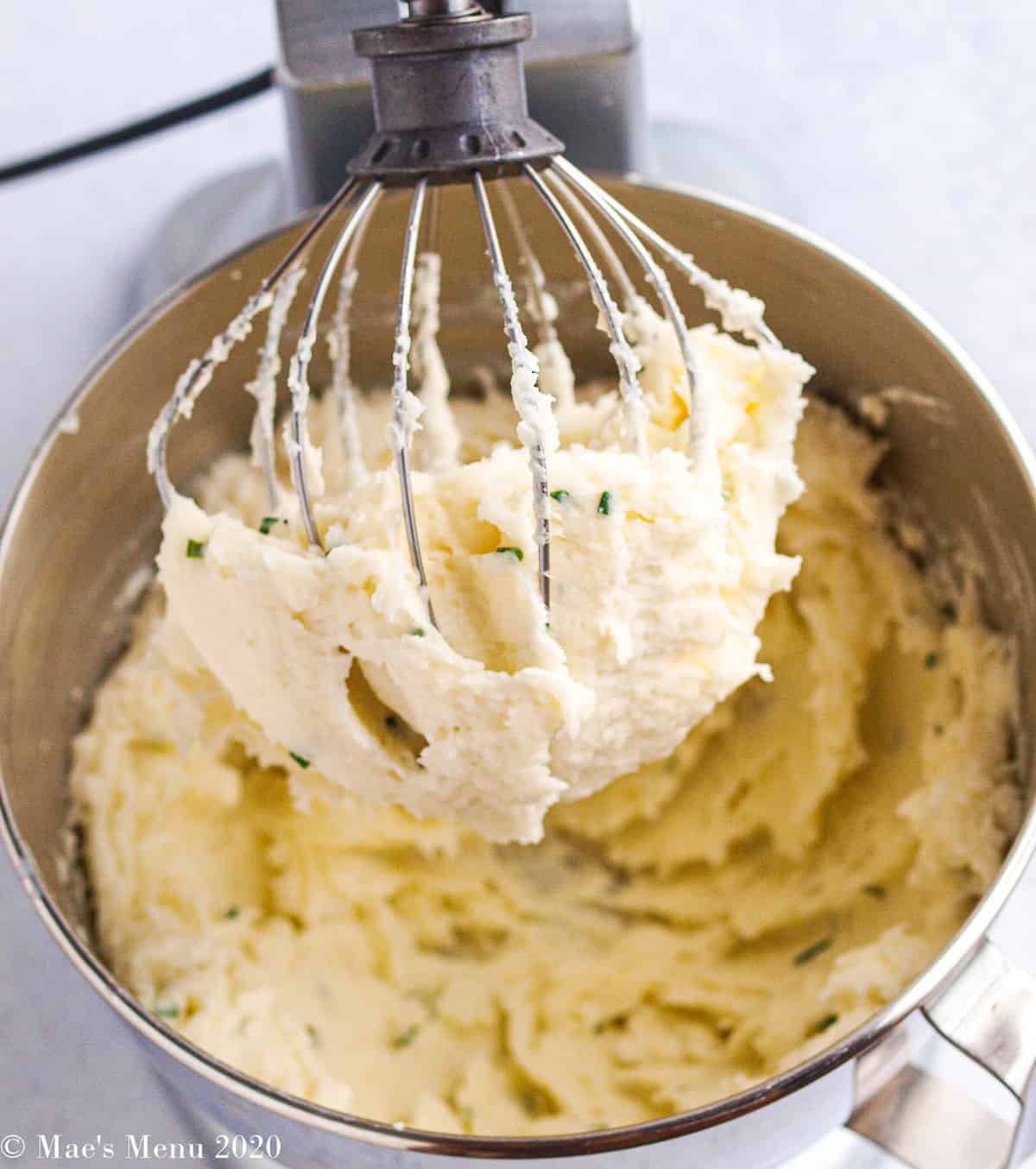 A stand mixer with mashed potatoes on a wire whisk attachment