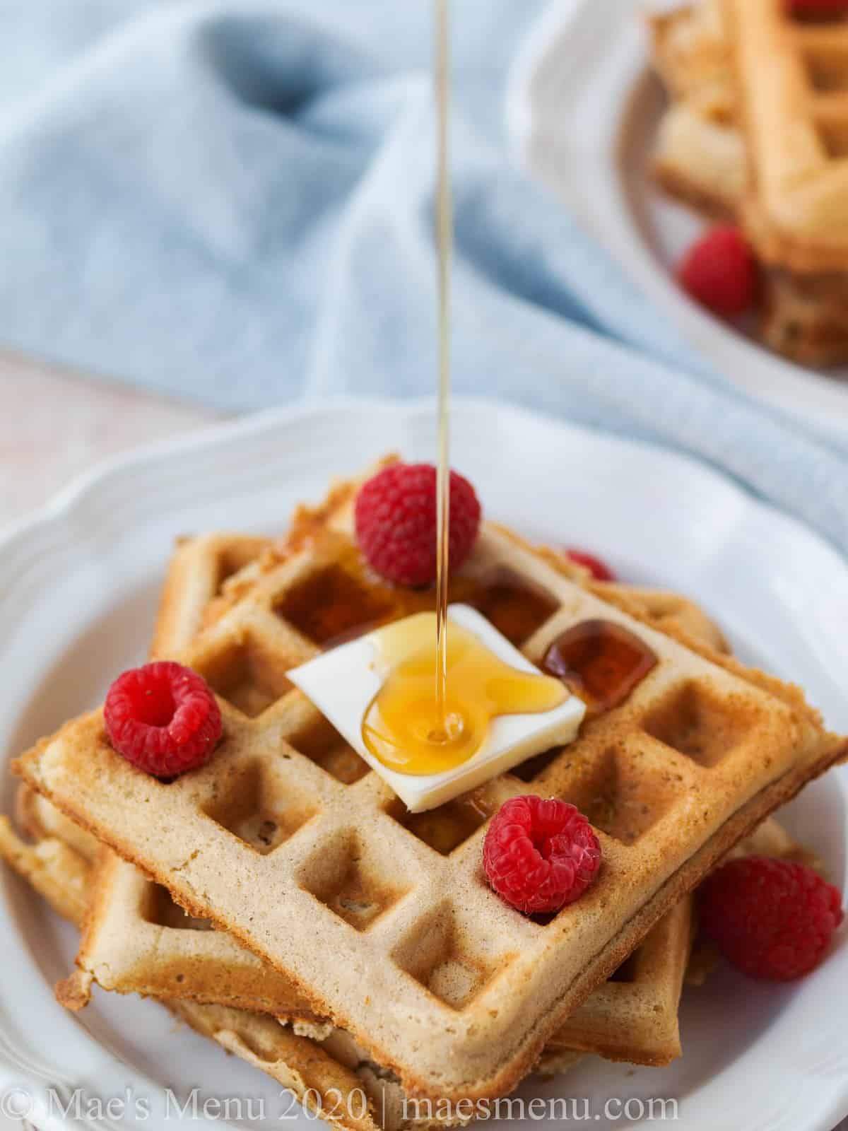 Syrup pouring over fluffy whole wheat belgian waffles.