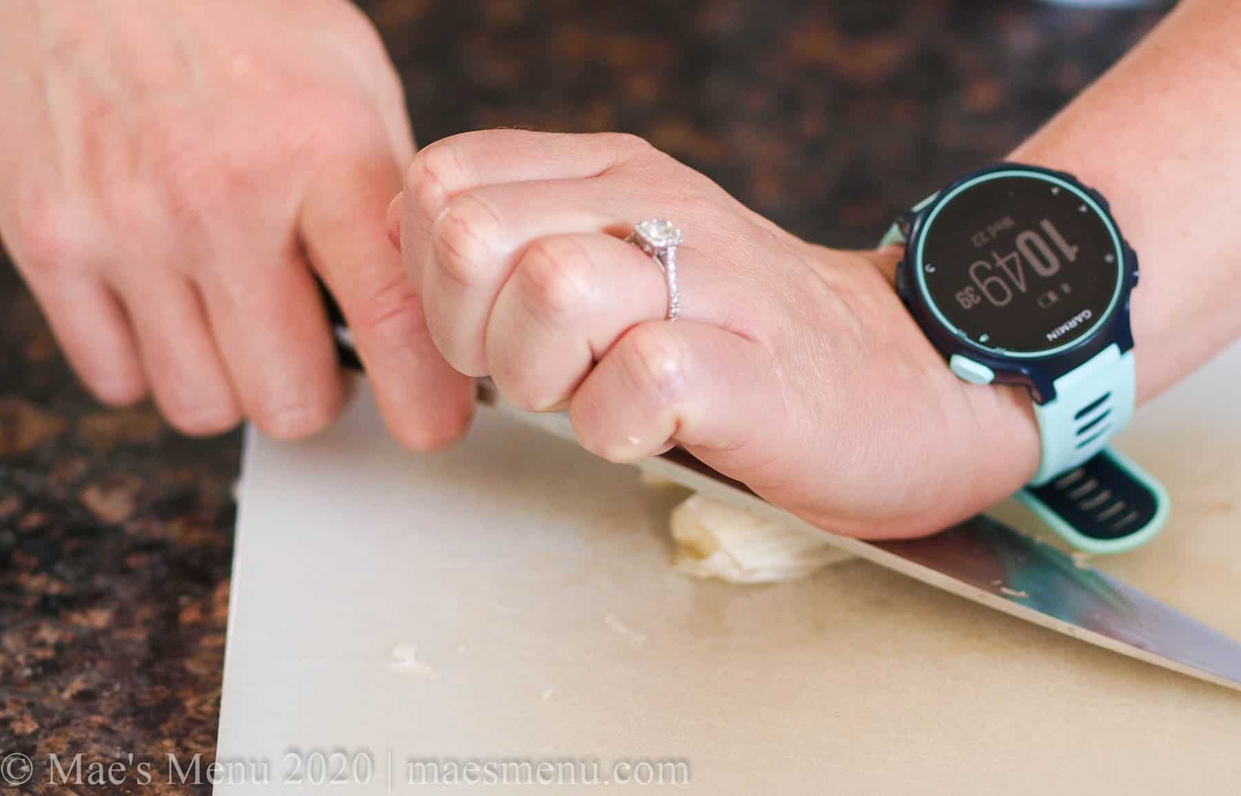 smashing the garlic clove with a chef's knife