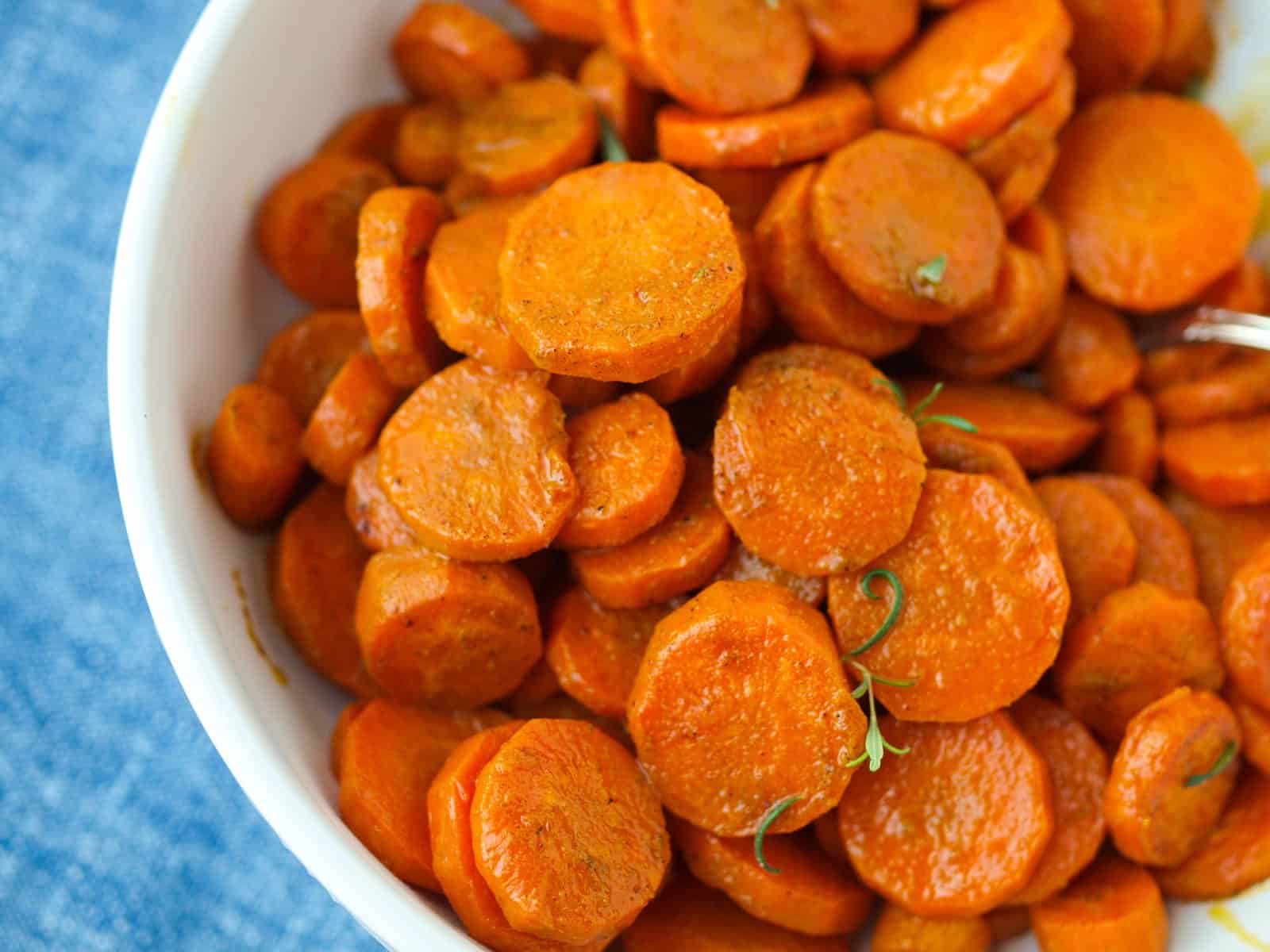 an up-close shot of Oven Roasted Turmeric & Cumin Carrots in a large white serving bowl