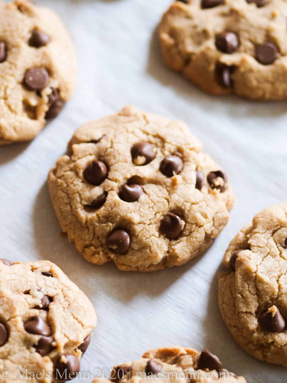 An overhead shot of chocolate chip cookies on a white parchment paper sheet