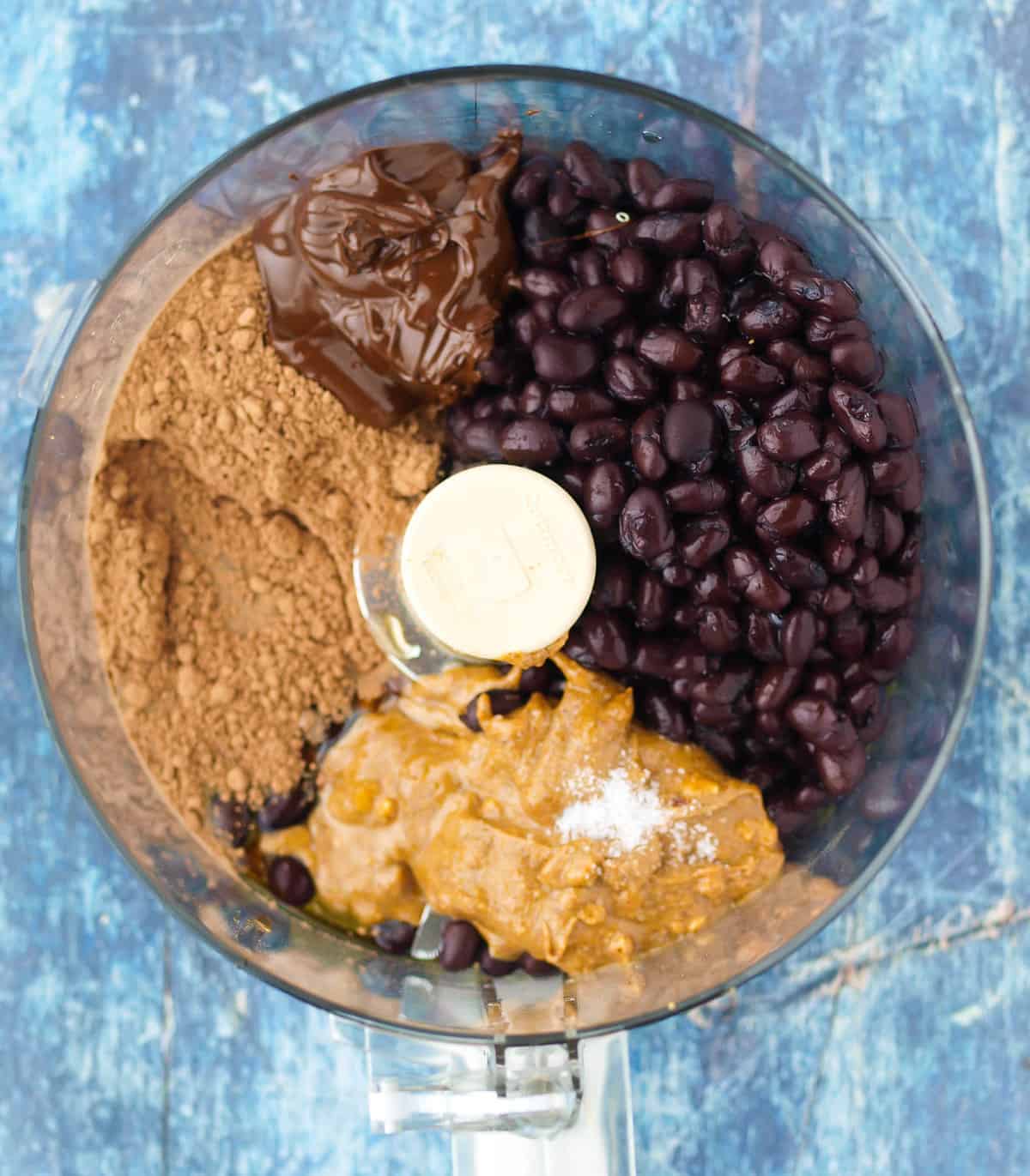 A food processor bowl full of ingredients for Chocolate Hummus. 