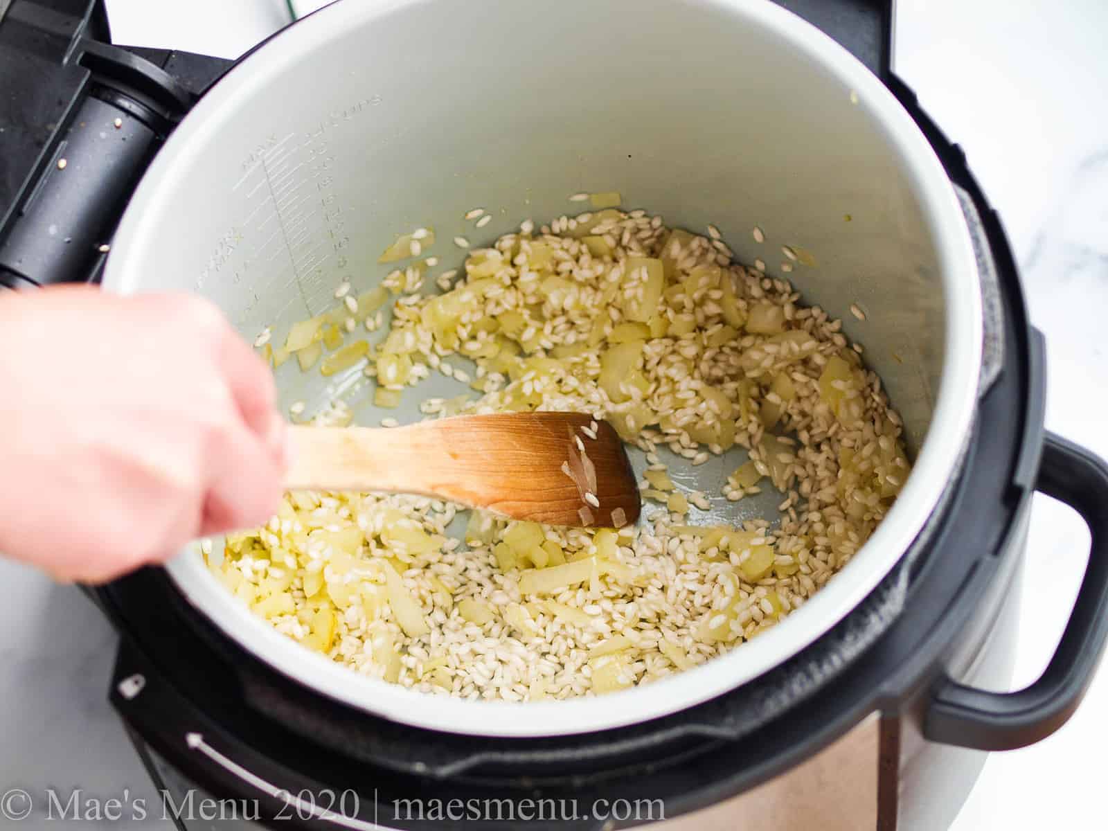 Stirring rice in the onions in th einstant pot 