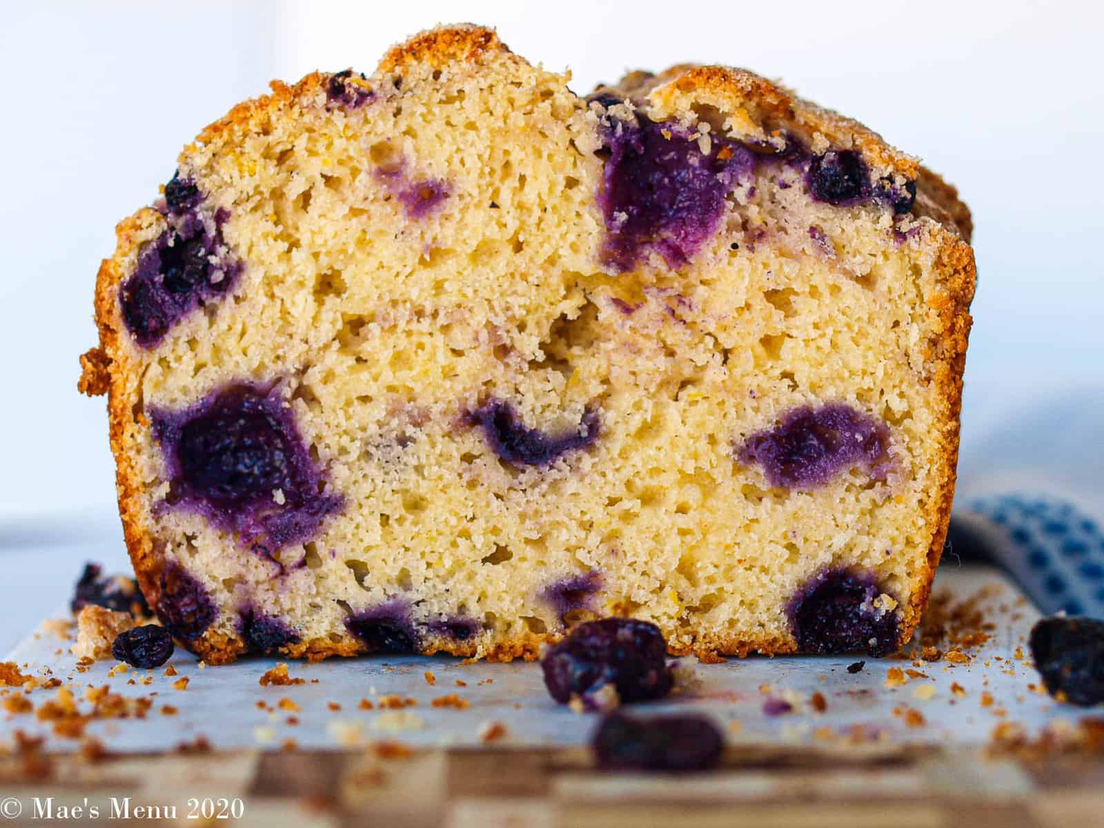 A side shot of a loaf of blueberry lemon bread on a cutting board.