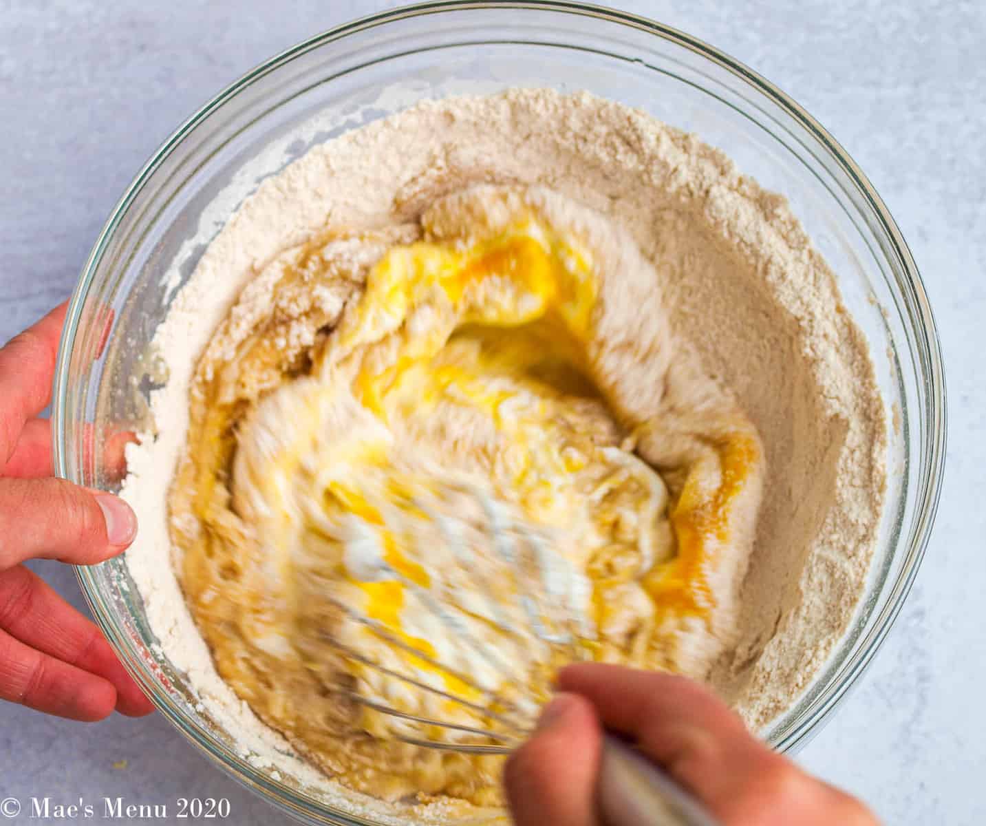 Mixing flour, lemon juice, lemon zest, sugar, melted butter, and eggs together in a large bowl with a whisk