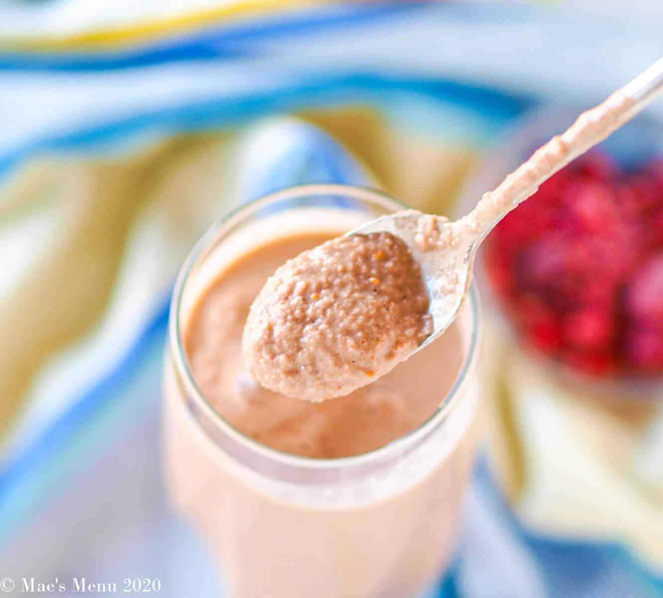 A spoonful of creamy raspberry smoothie held over a glass of the smoothie