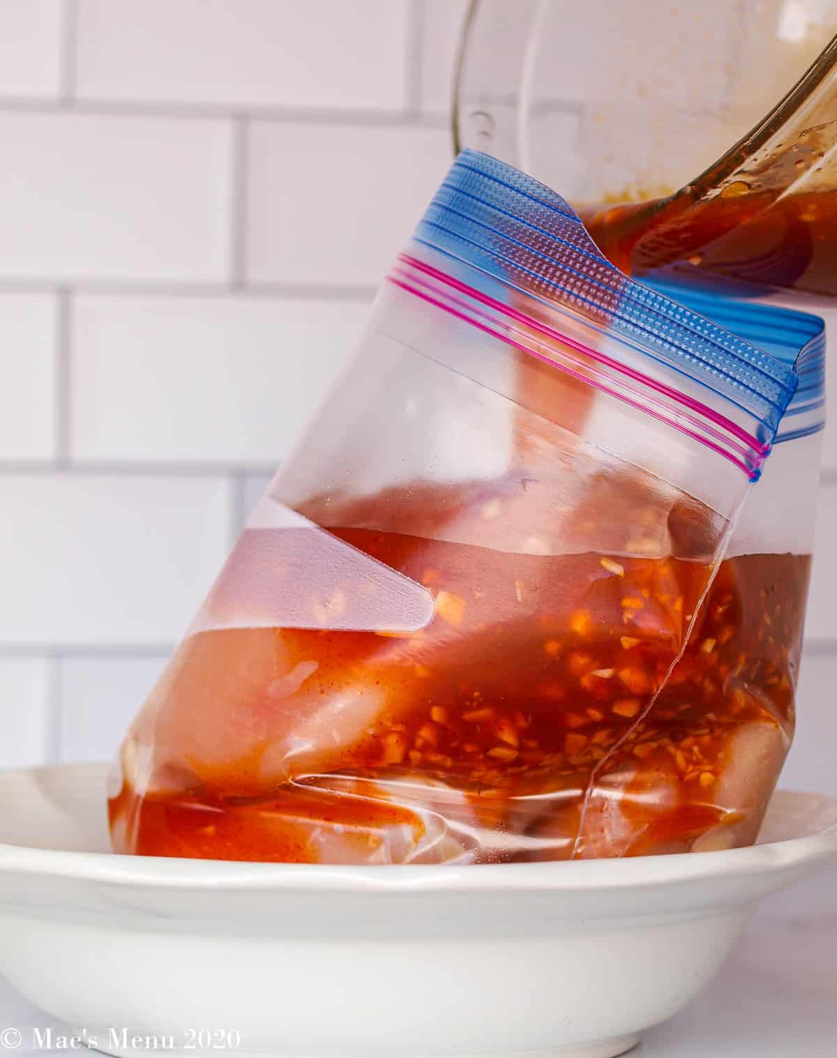 Pouring the marinade into a ziploc bag with the chicken