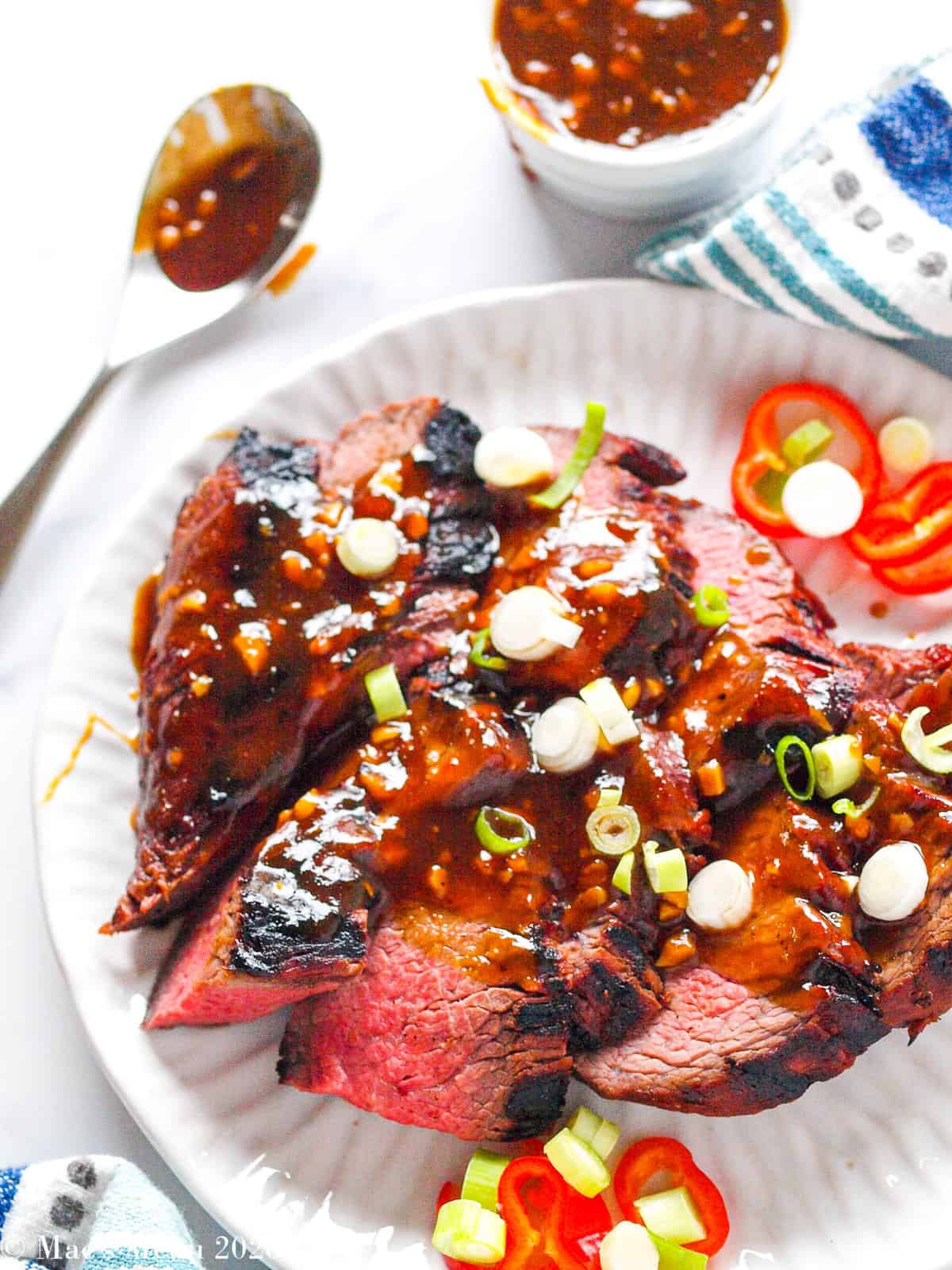 Grilled tri tip steak with marinade sauce on top.