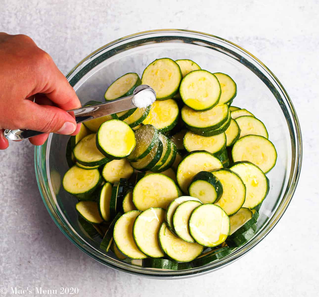Pouring salt until a mixing bowl of zucchini