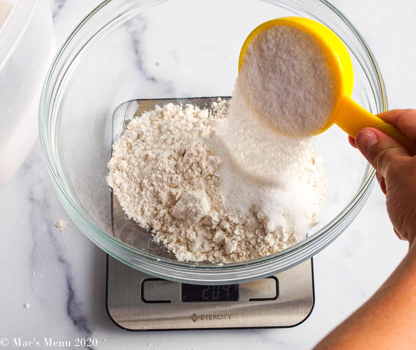 Pouring sugar into the flour in the bowl
