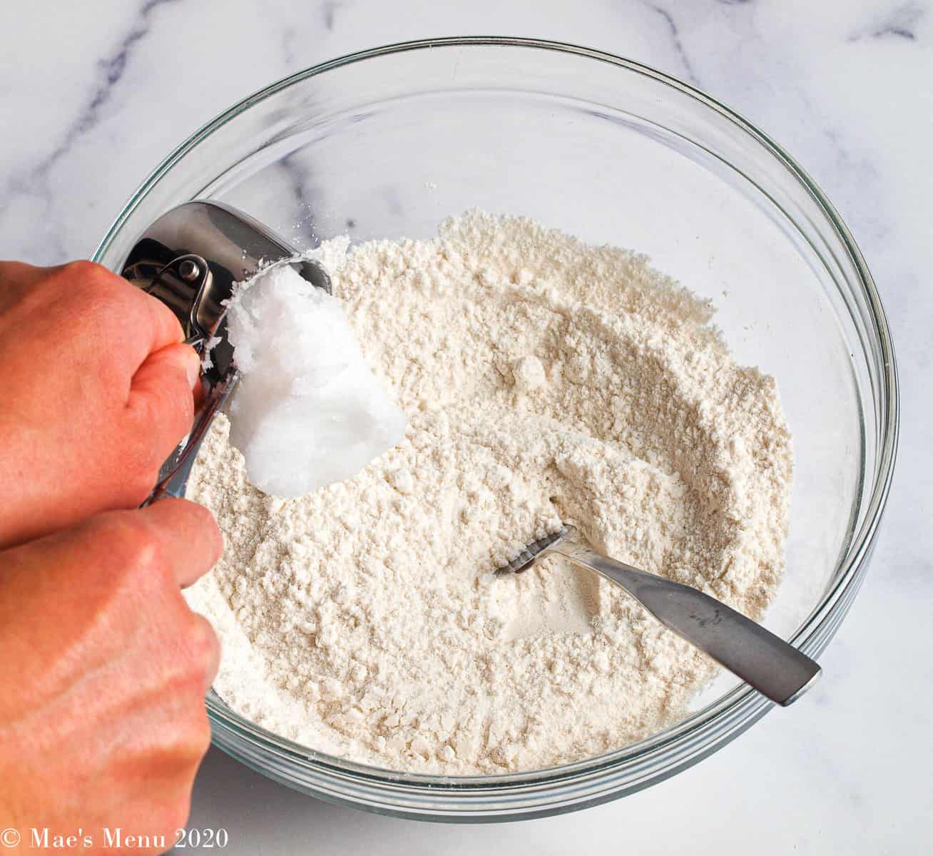 Pouring coconut oil into the flour