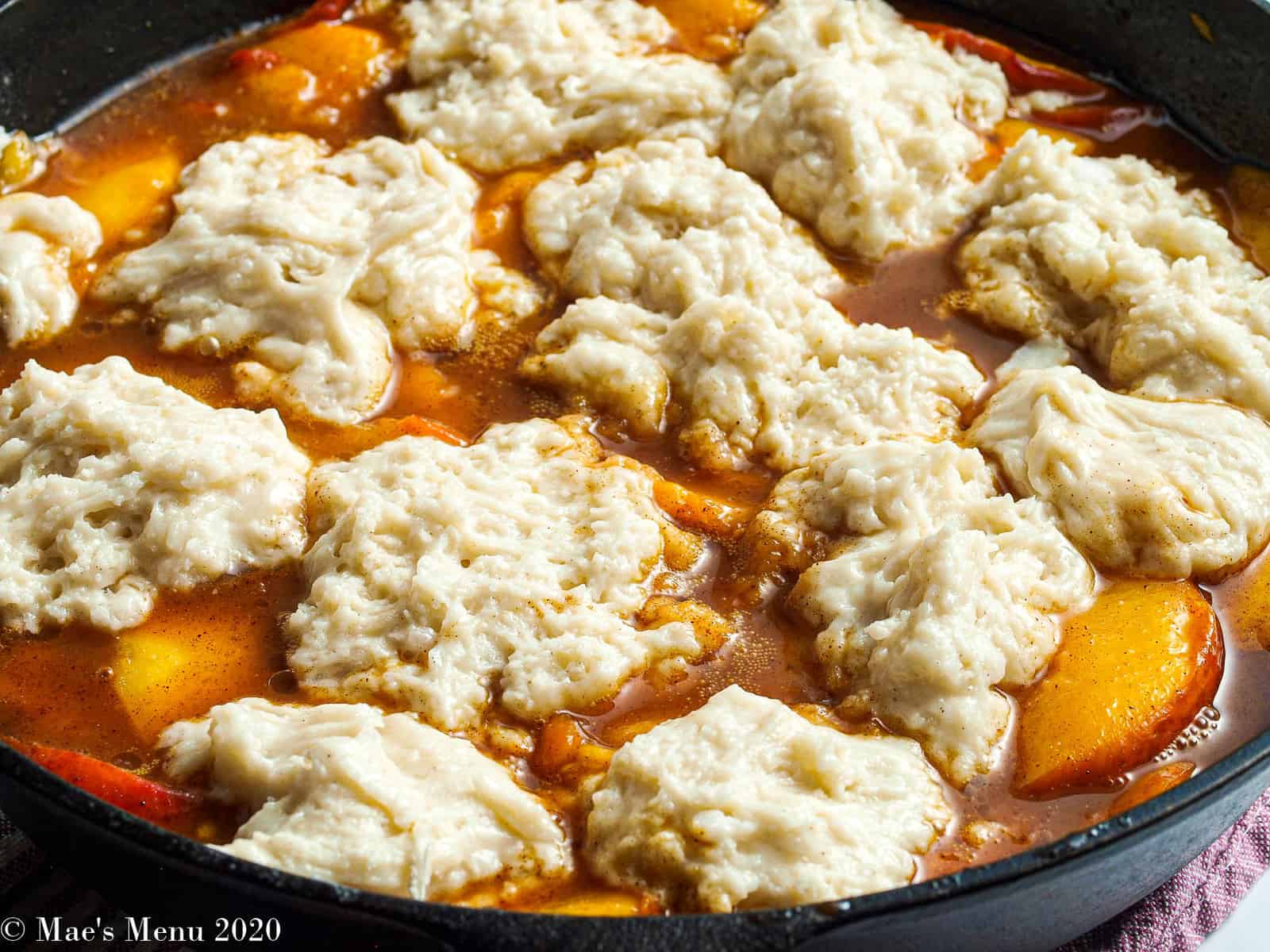 A side shot of peach cobbler in a cast iron skillet before baking.