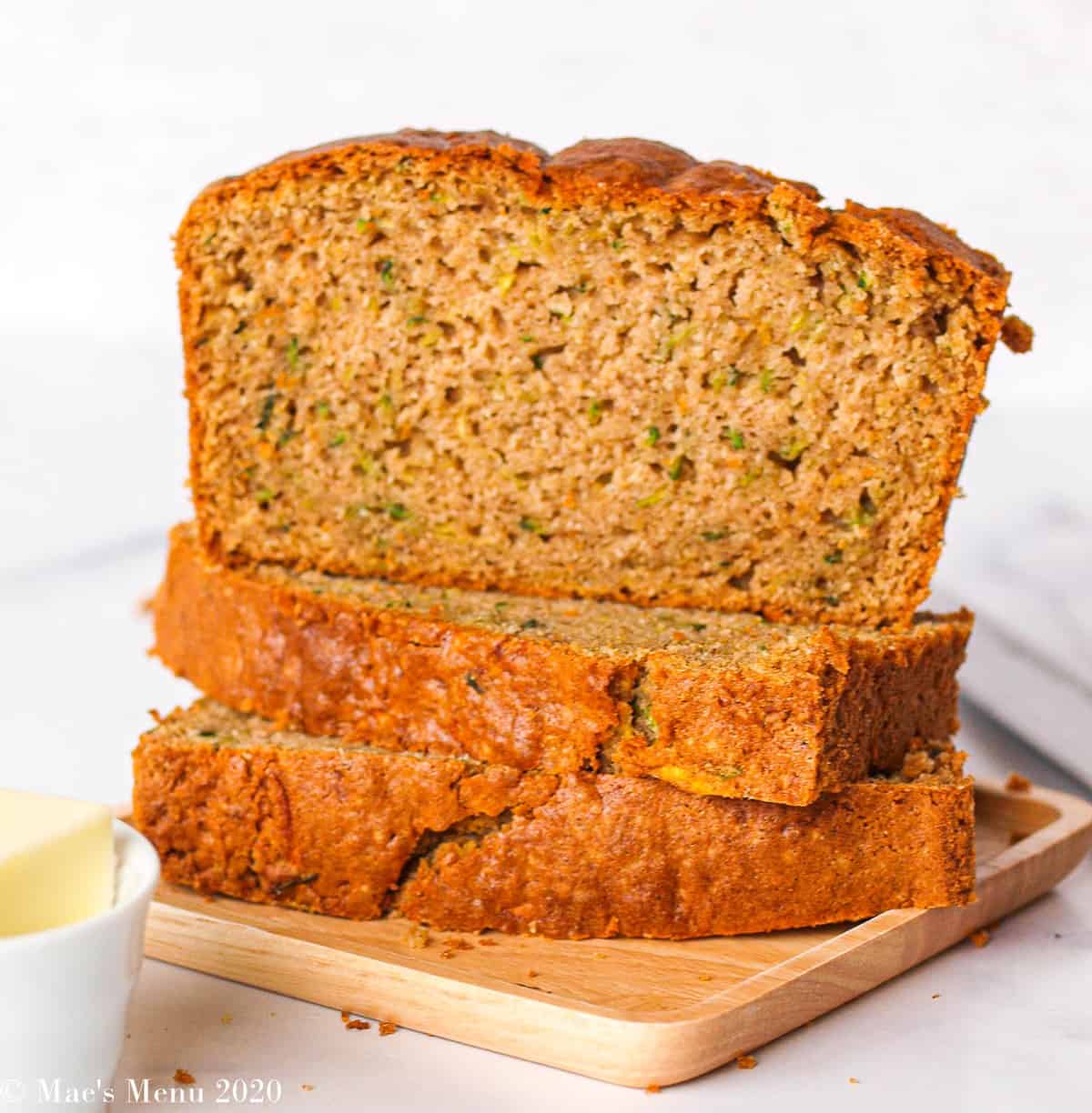 Two pieces of zucchini bread stacked on their side with a piece of bread sitting on top. 