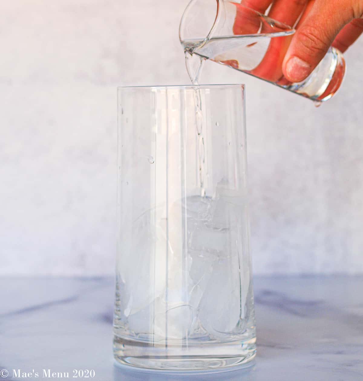 Pouring a shot of vodka into a glass of ice