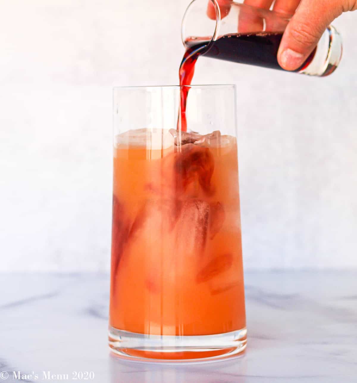 Pouring pomegranate juice into a glass of grapefruit juice
