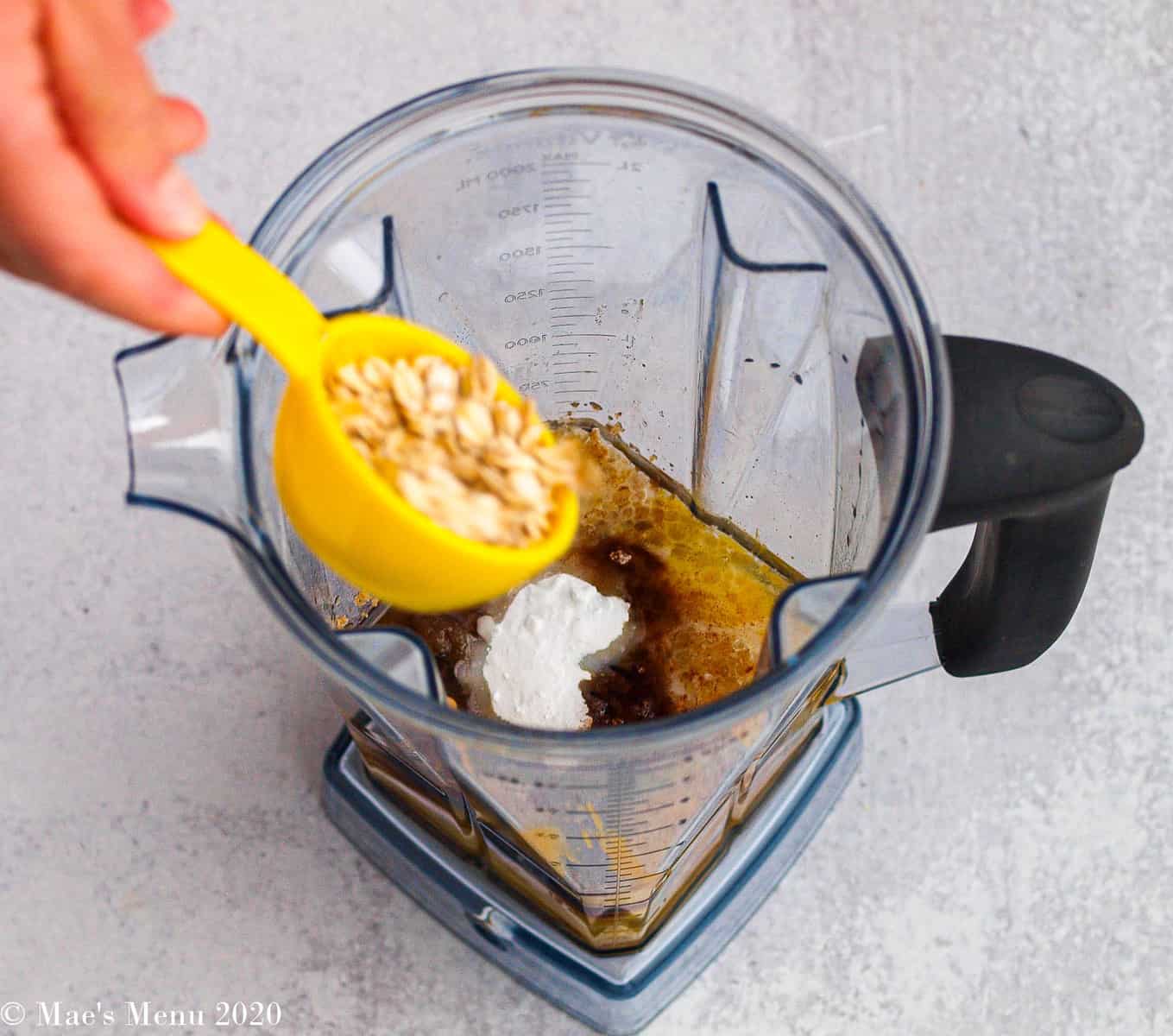 Adding oats to a blender of pumpkin, coconut oil, and other ingredients