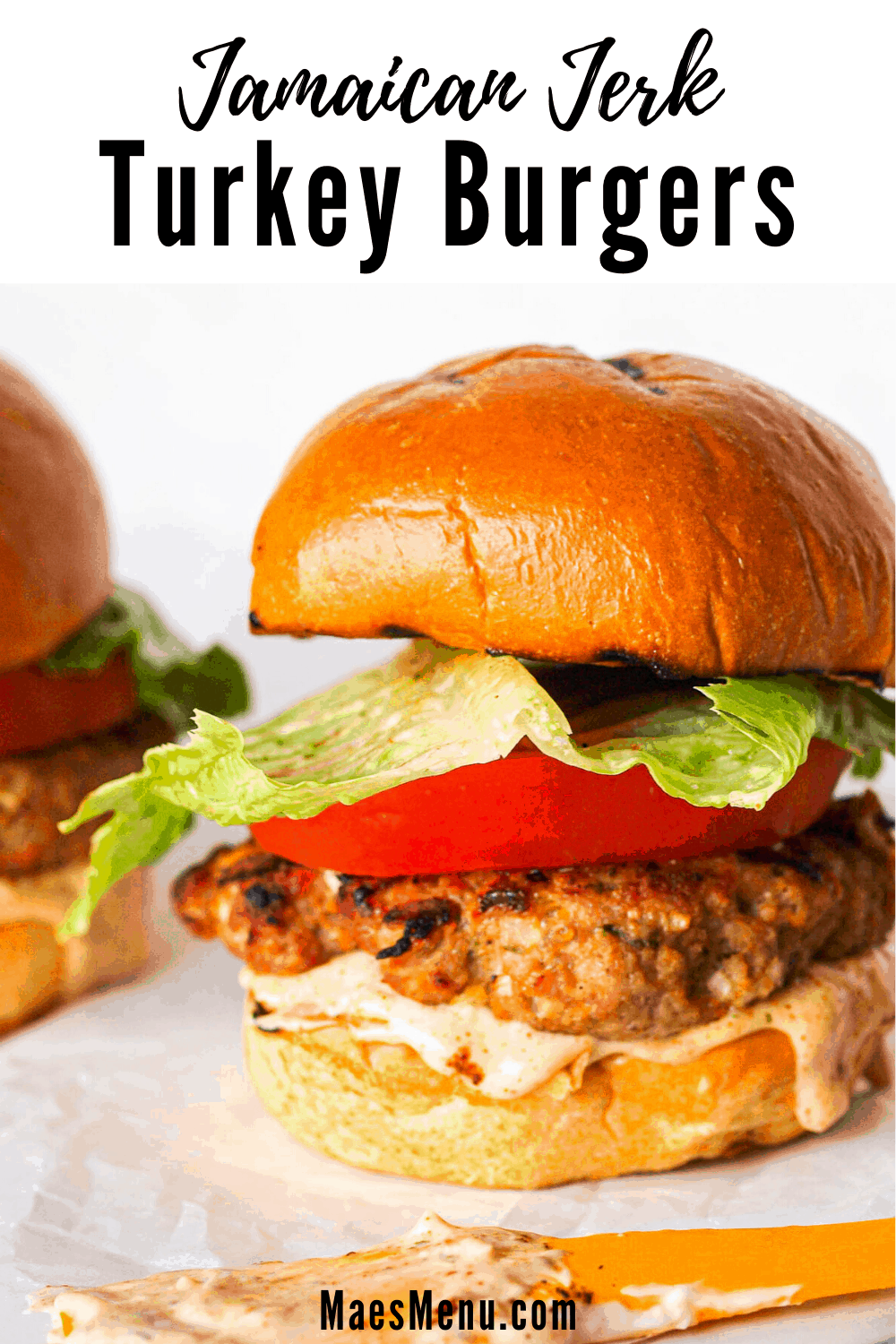 A pinterest pin for Jamaican Jerk Turkey Burgers with an up-close picture of a turkey burger with a spatula in the foreground.