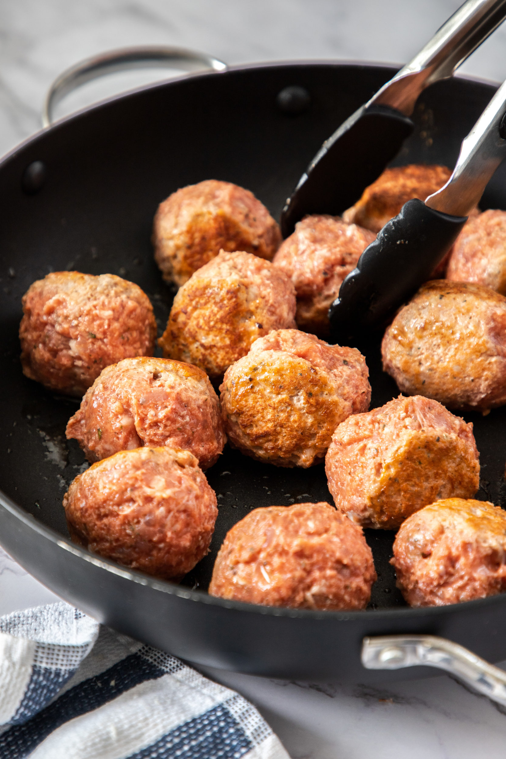 Meatballs cooking in a nonstick skillet