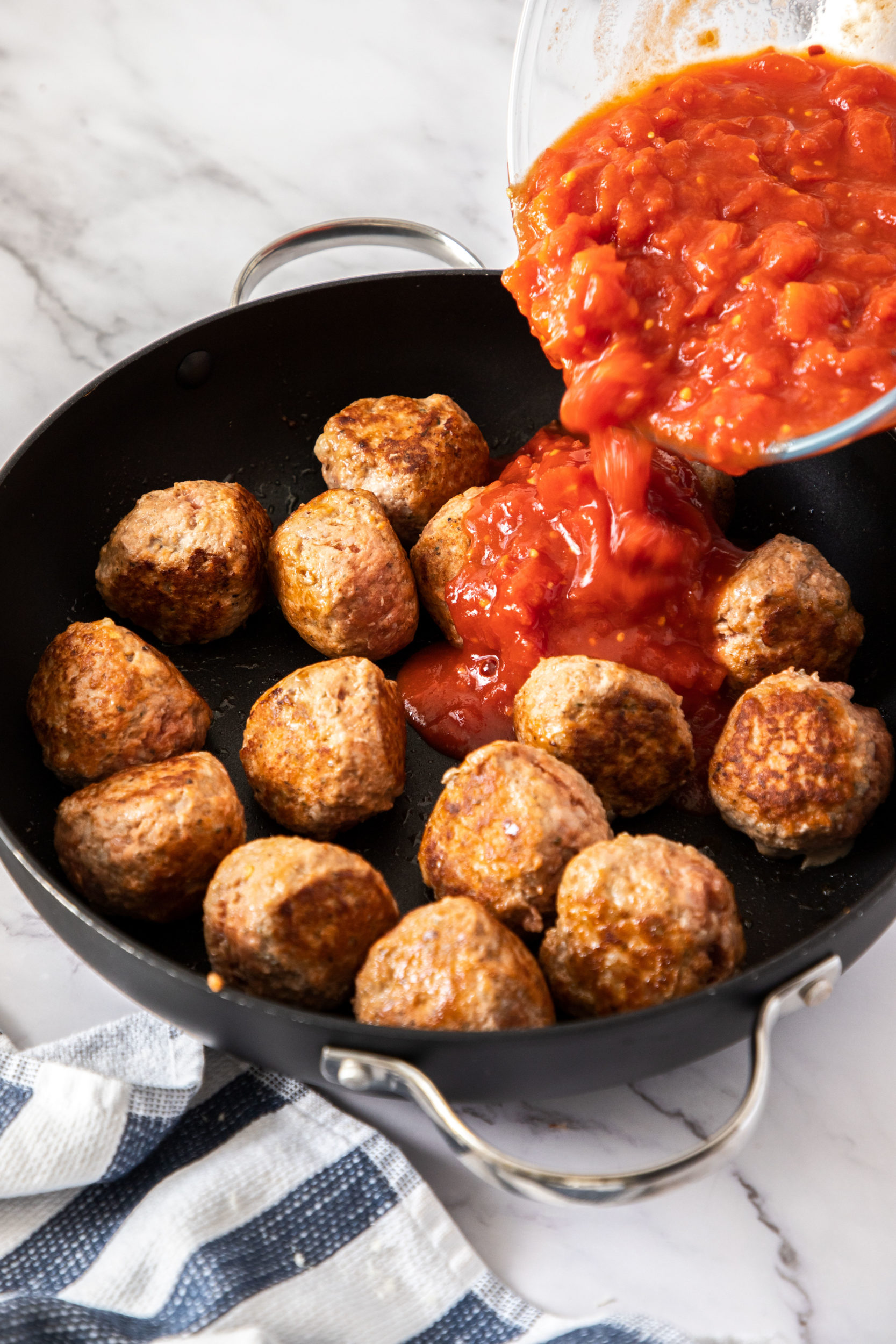 Pouring the tomato sauce in with the meatballs