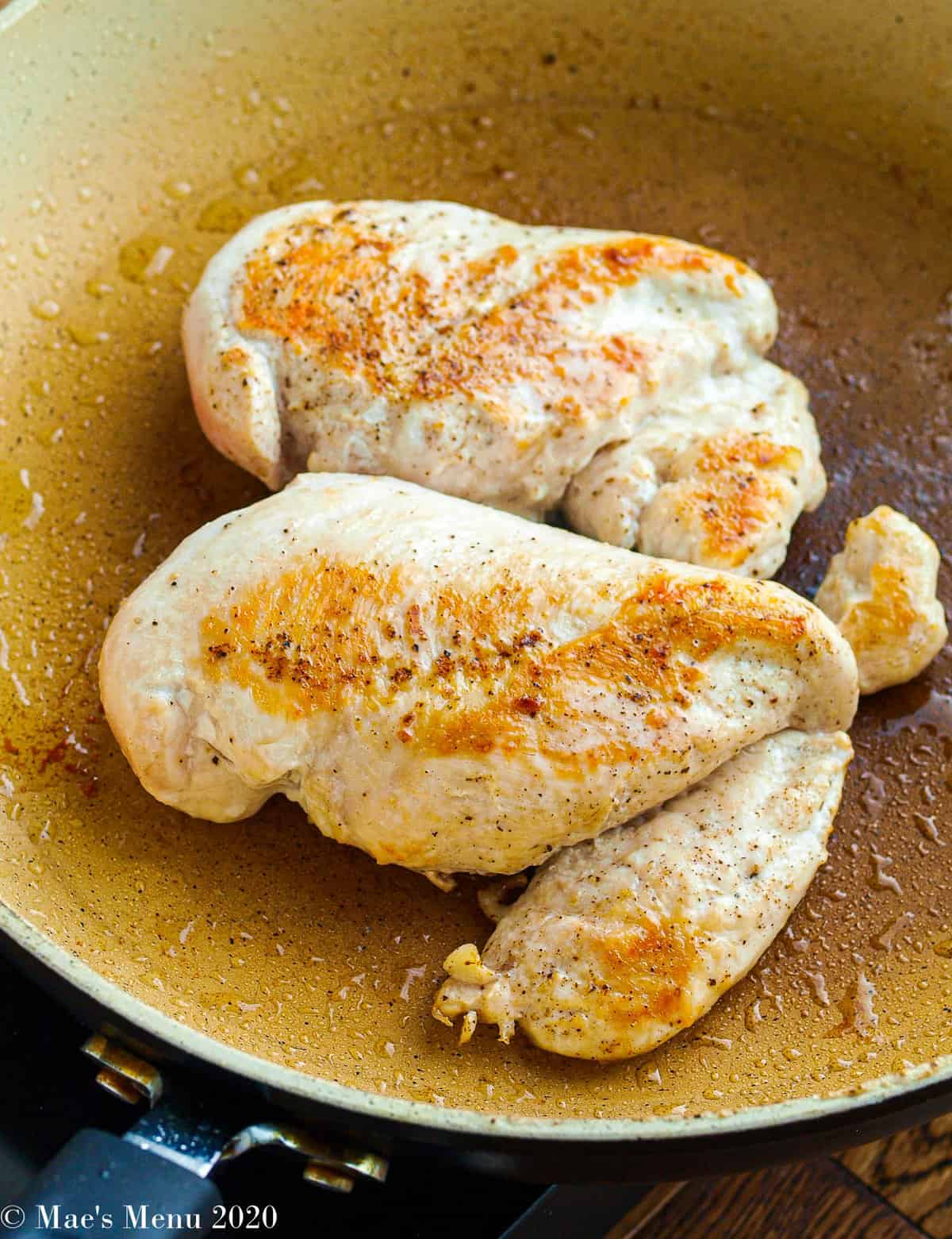 Two chicken breasts in a saute pan