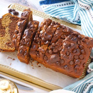 An overhead shot of a loaf of chocolate peanut butter banana bread sliced on a cutting board