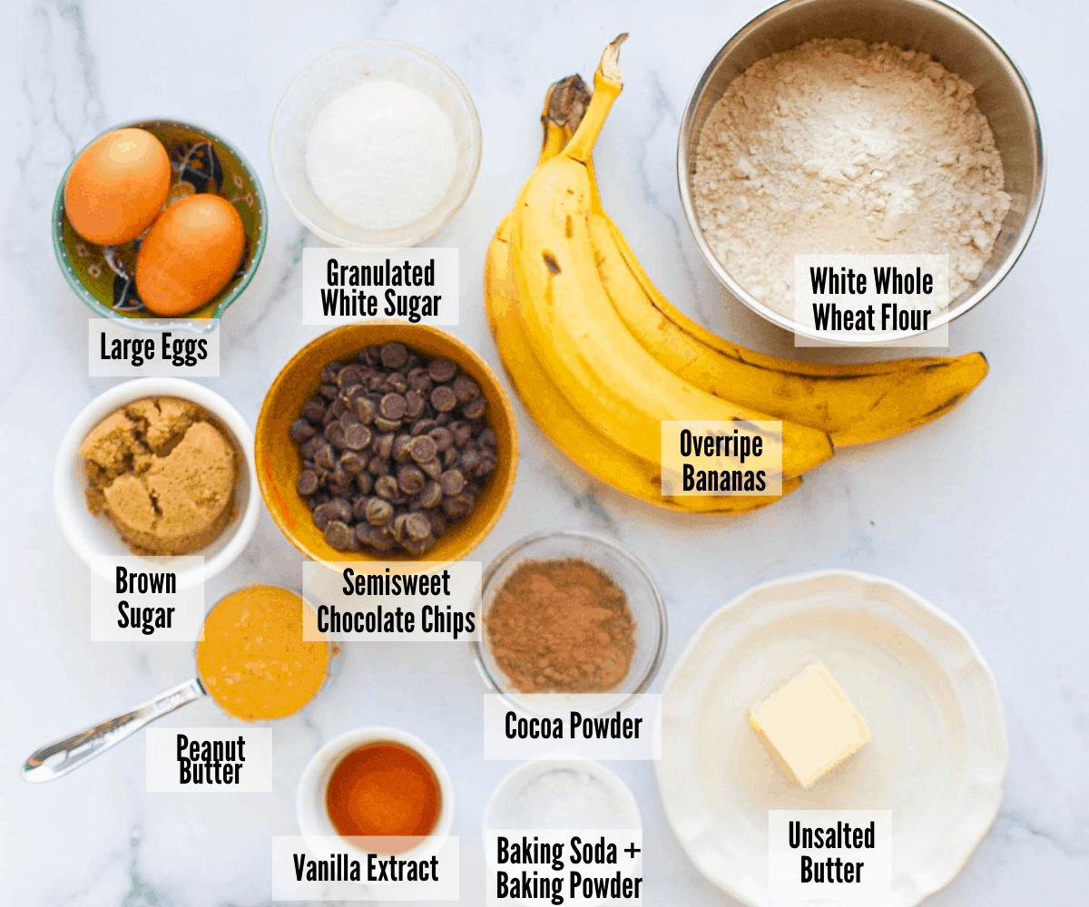 All the ingredients for chocolate peanut butter banana bread: large eggs, white sugar, brown sugar, semisweet chocolate chips, overripe bananas, white whole wheat flour, peanut butter, cocoa powder, unsalted butter, baking powder, and baking soda