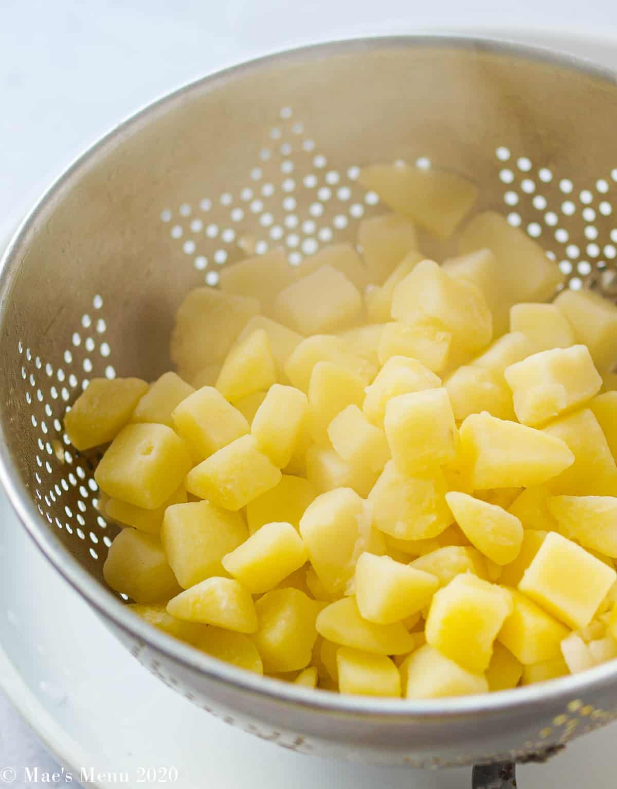 A strainer full of hot cooked potatoes 