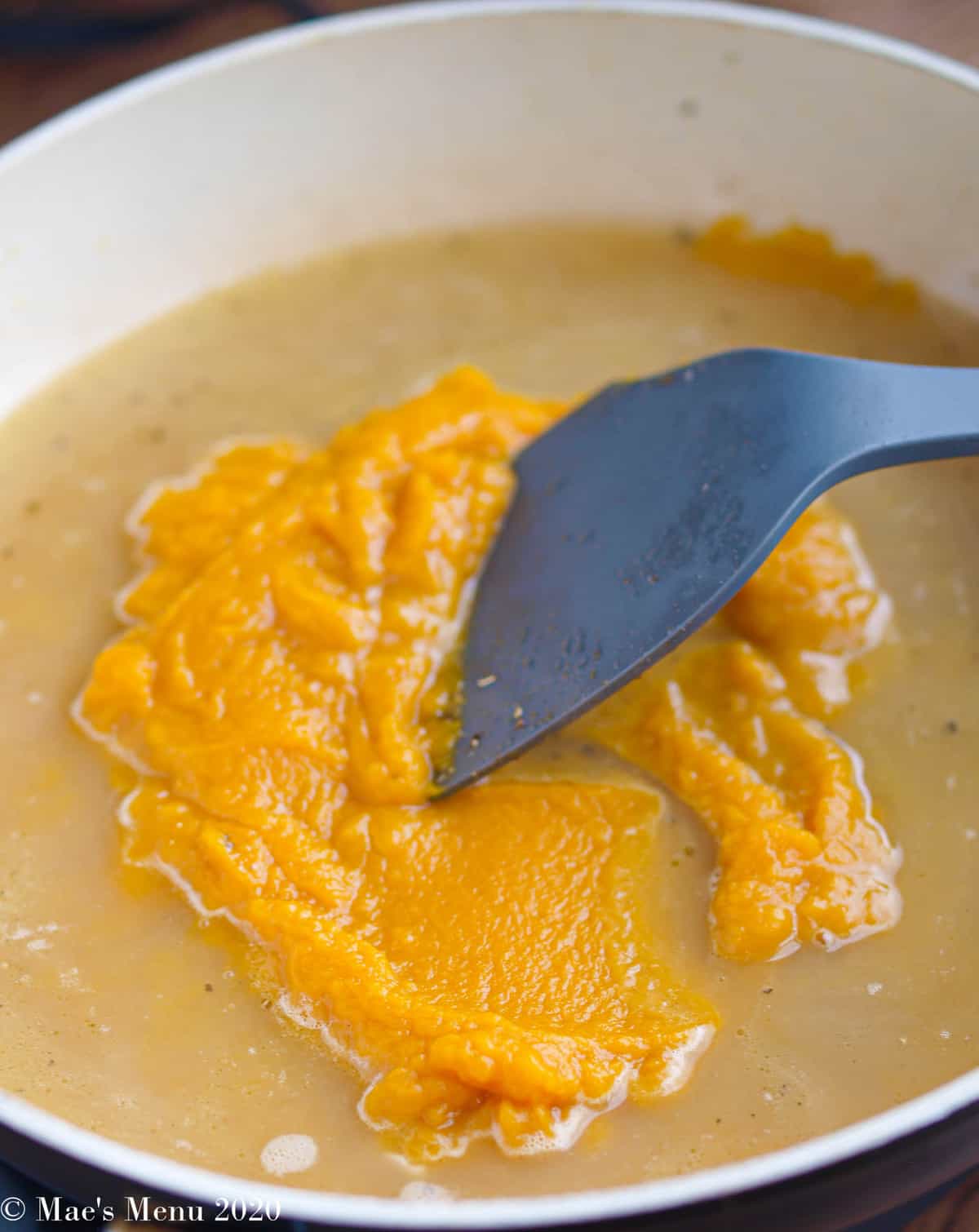 Canned pumpkin added into the non-stick pan with a spatula