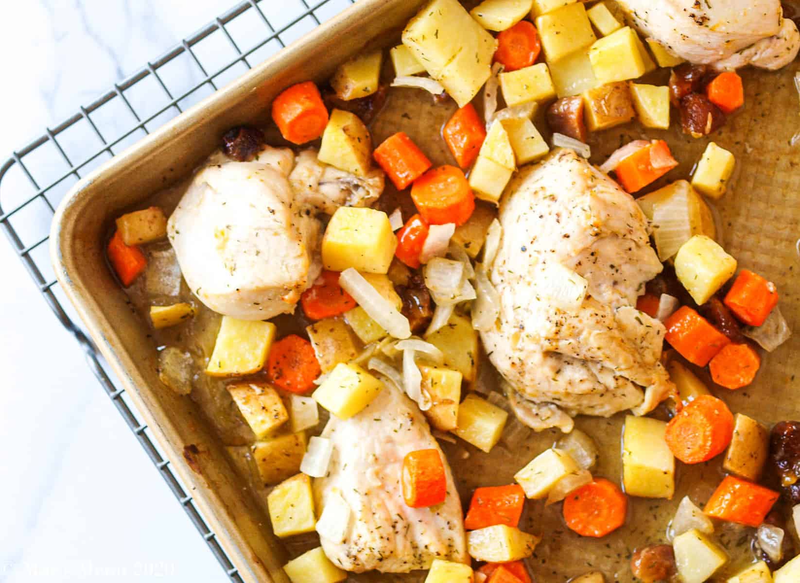 An over head shot of a corner of a sheet pan with apricot chicken and potatoes