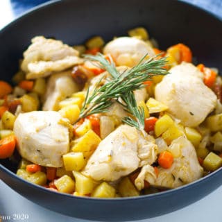 an up-close angle shot of a black bowl of the sheet pan apricot chicken and vegetables