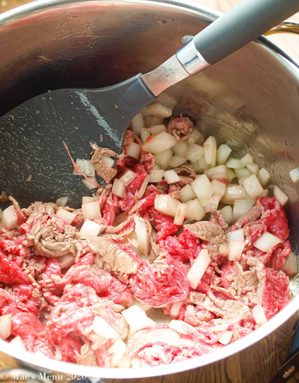 Sauteing the steak and onions in a dutch oven