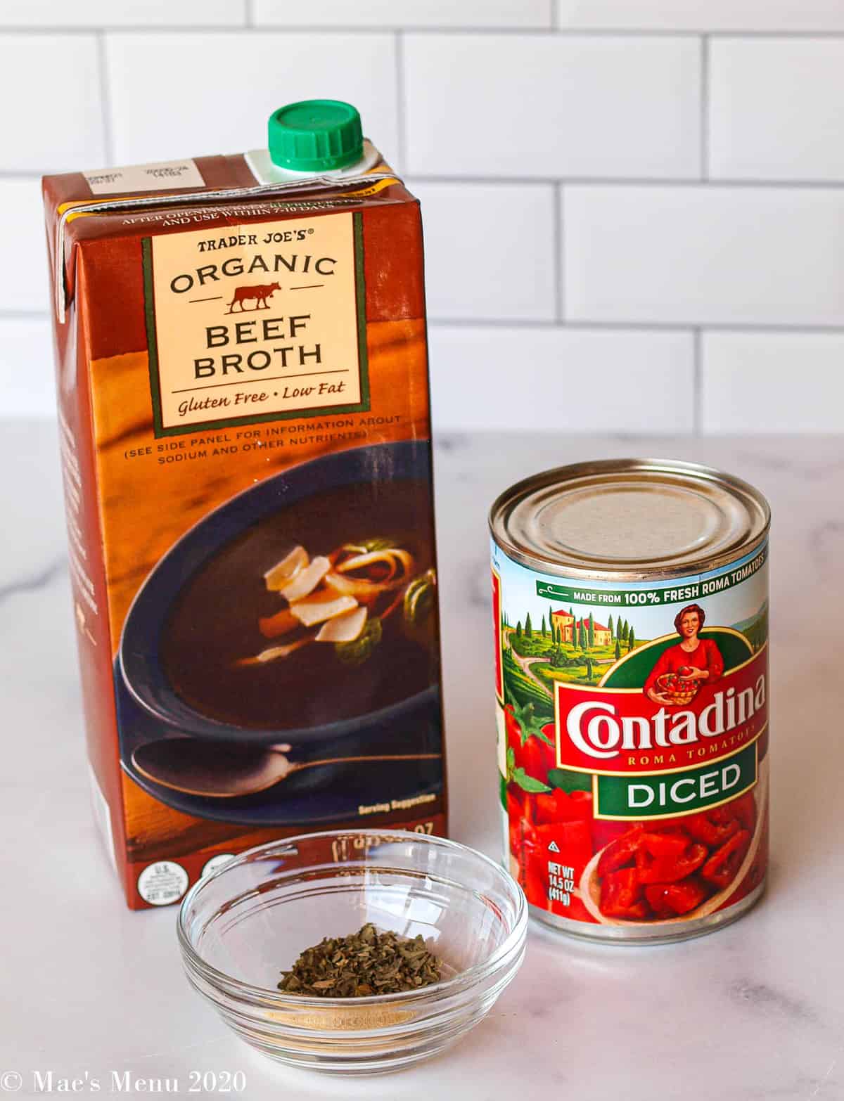 A can of tomatoes, quart of beef soup, and small dish of seasonings for the soup