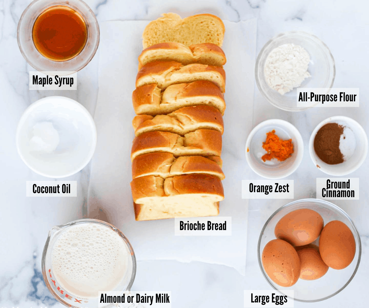 All the ingredients for brioche french toast: maple syrup, coconut oil, almond milk, salt, cinnamon, eggs, all-purpose flour, orange zest, and brioche bread