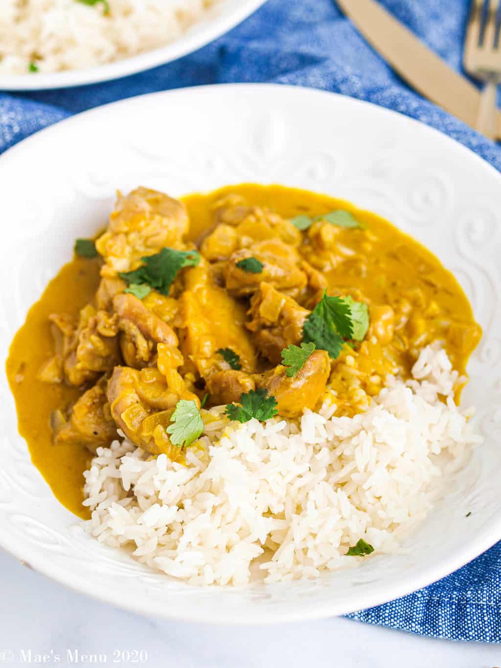 A side angle shot of a white bowl of peanut butter chicken curry