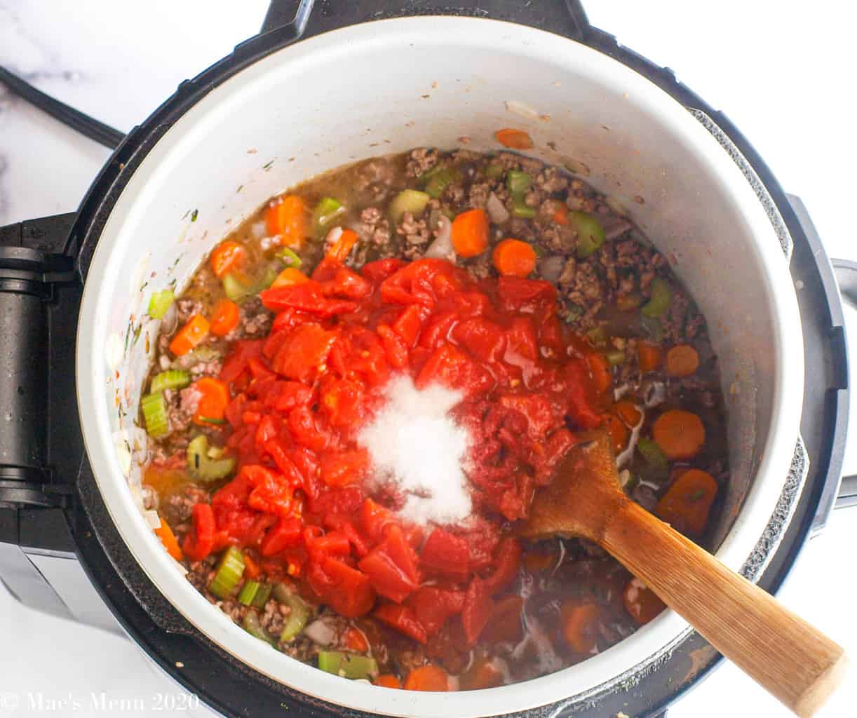 Tomatoes, tomato paste, and salt added into the meat and veggies in the pressure cooker 