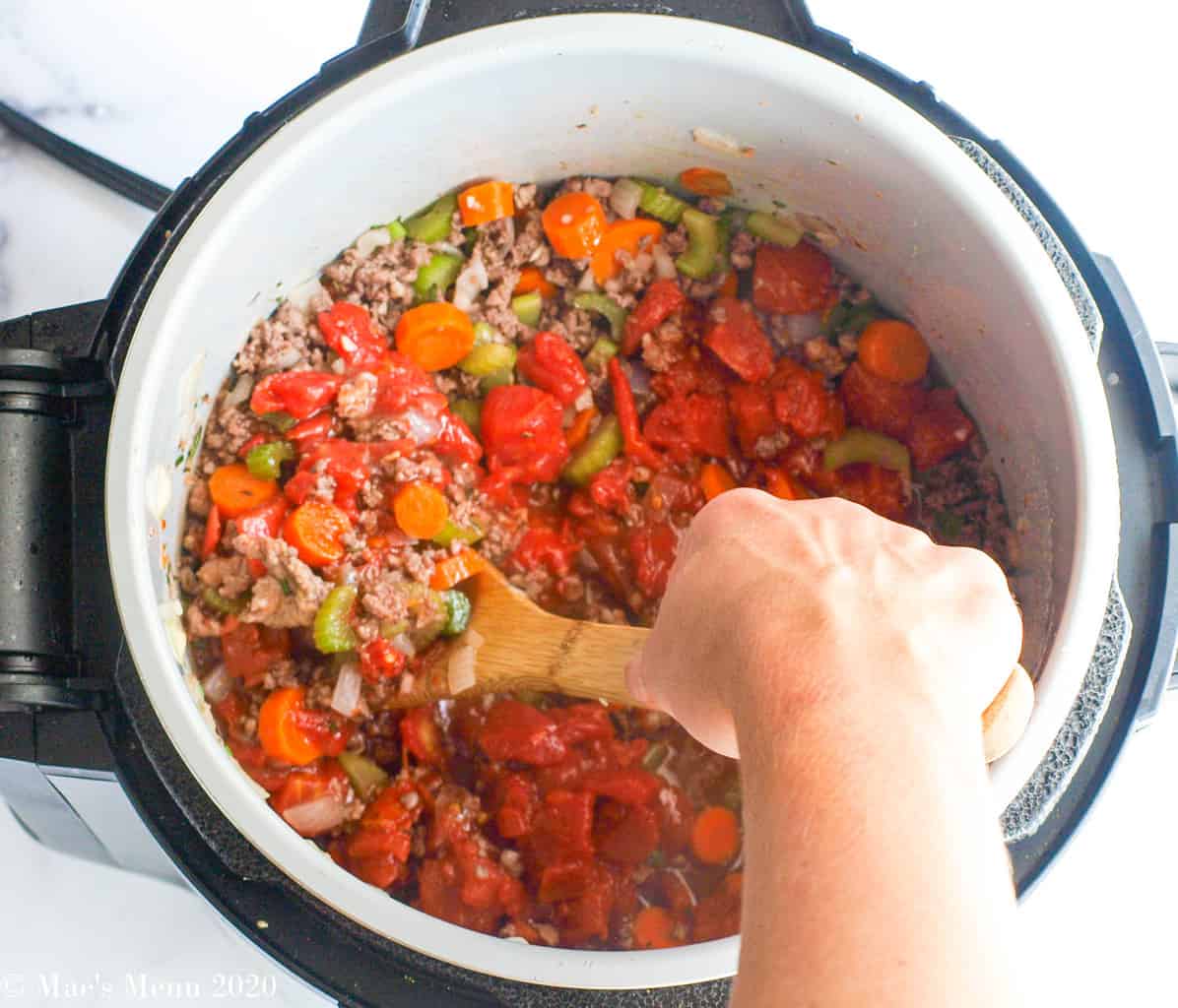 Stiring the meat and veggies in the pressure cooker