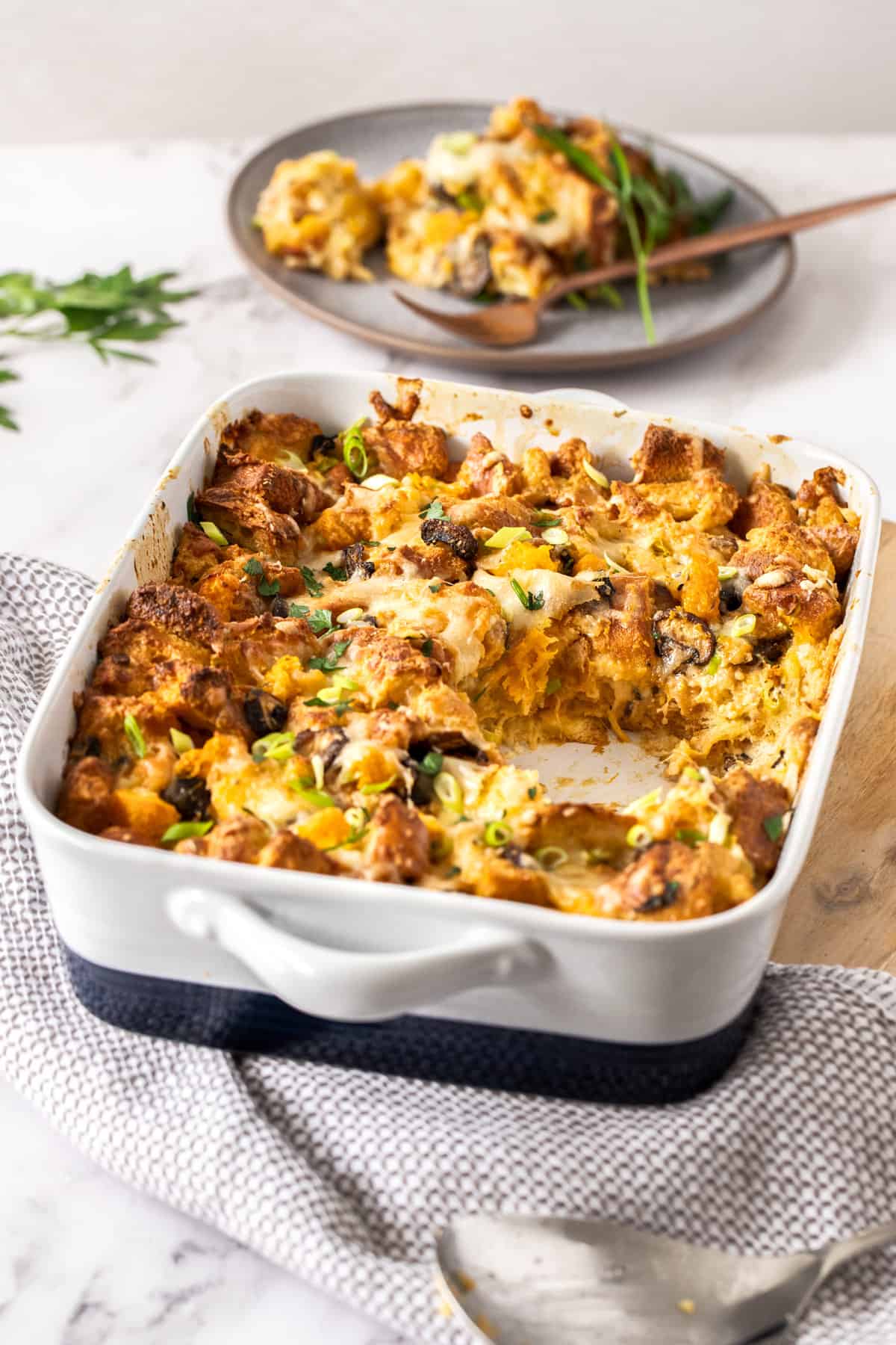 A pan of savory bread pudding with a serving taken out of it.
