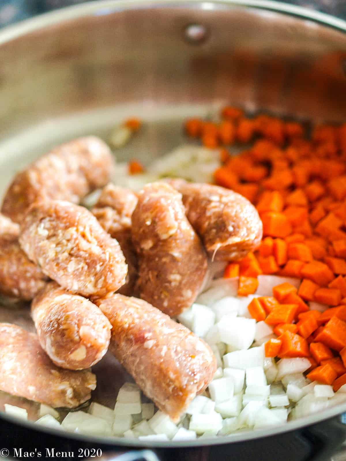 Italian sausage, carrots, and onion in a large saute pan