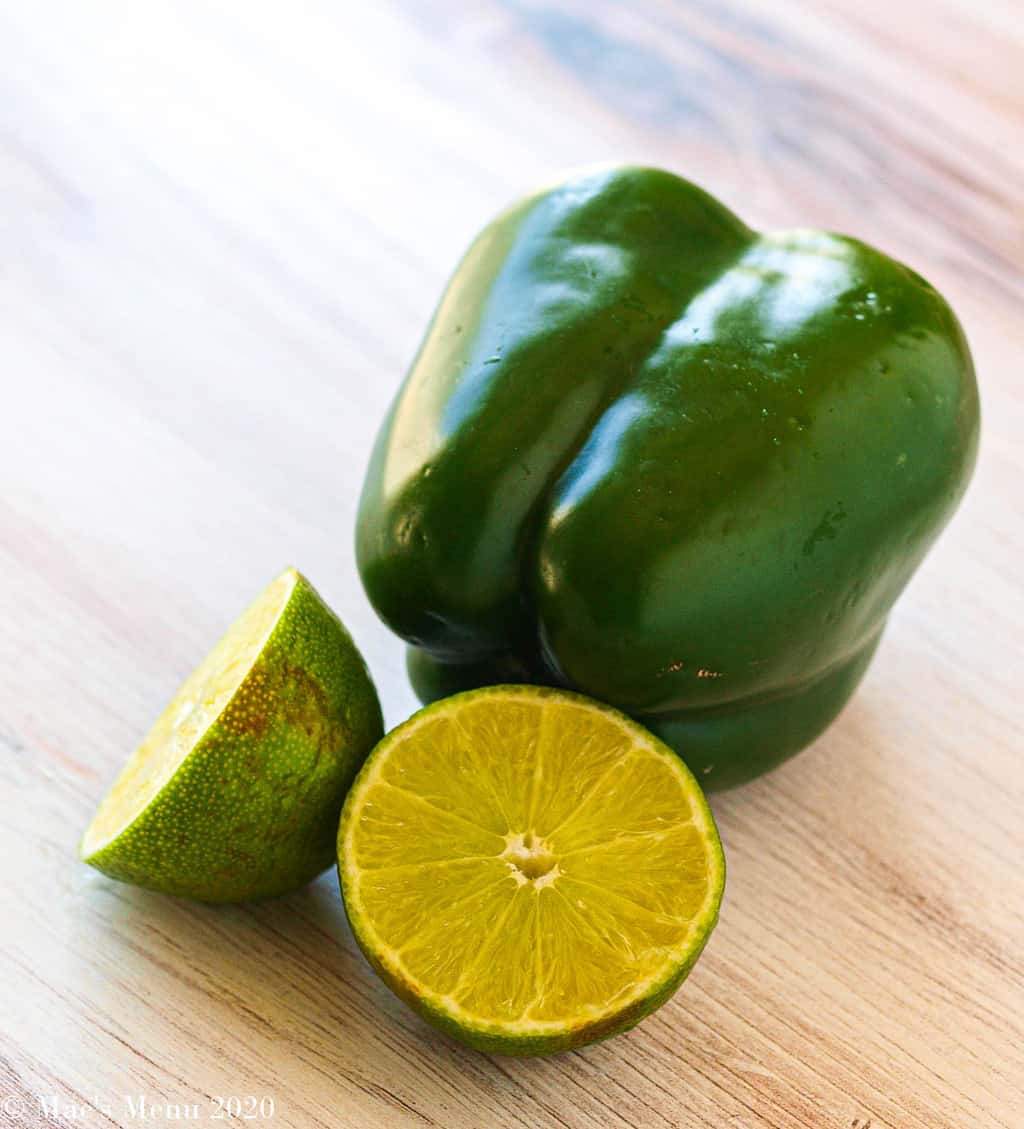 A green pepper next to 2 lime halves