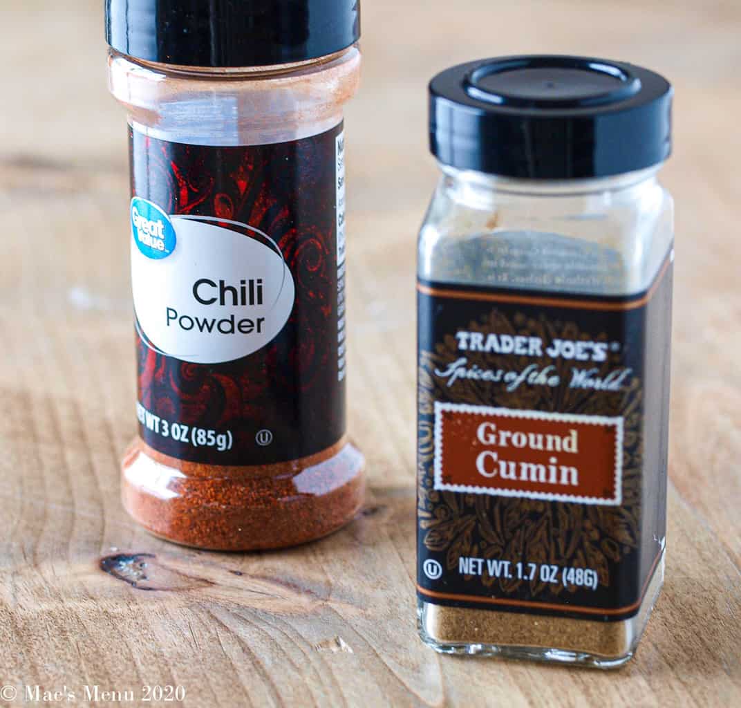 A bottle of chili powder next to a bottle of ground cumin